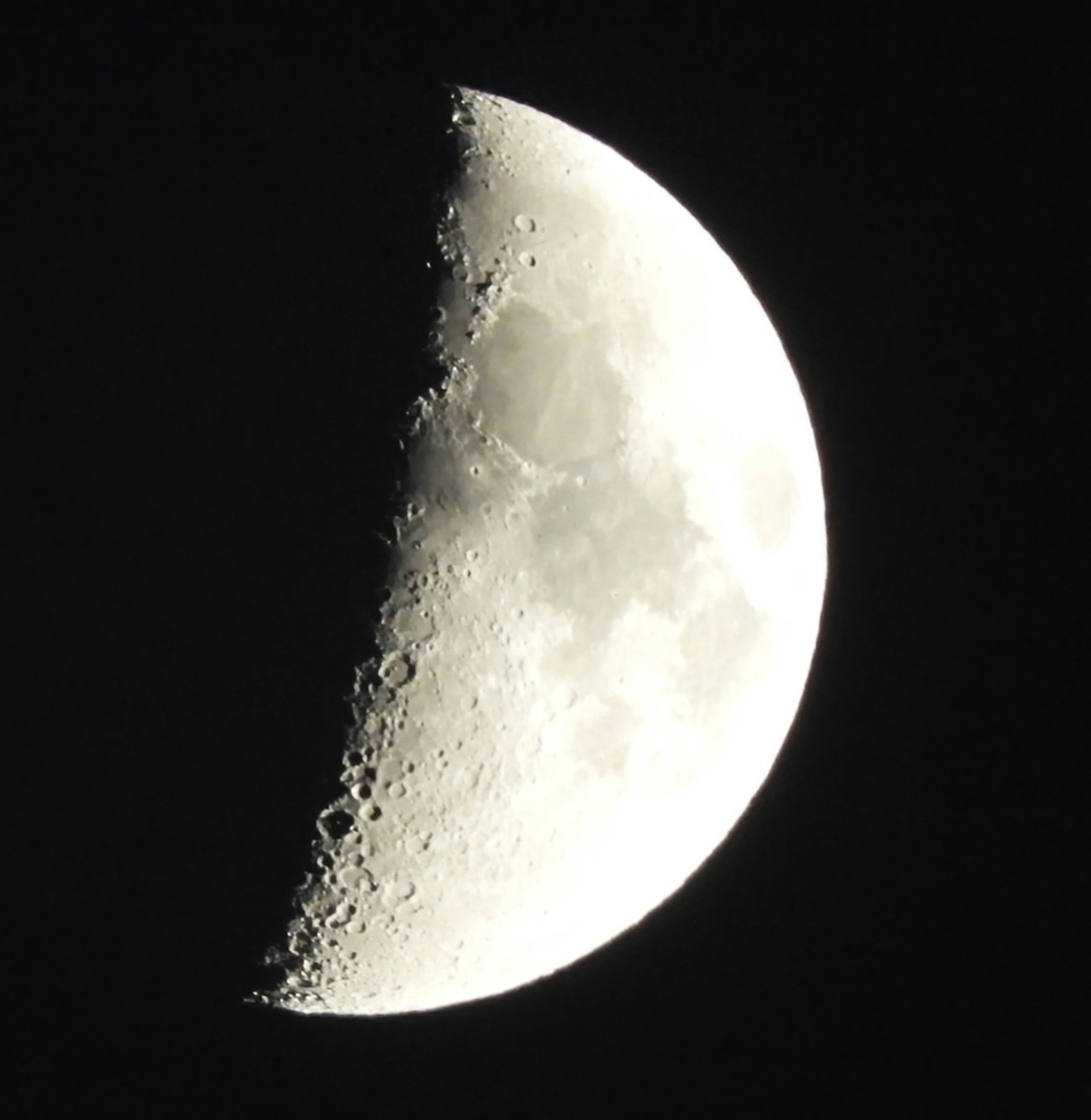 Zunehmender Mond mit heller Oberfläche und Kratern vor einem dunklen Himmel