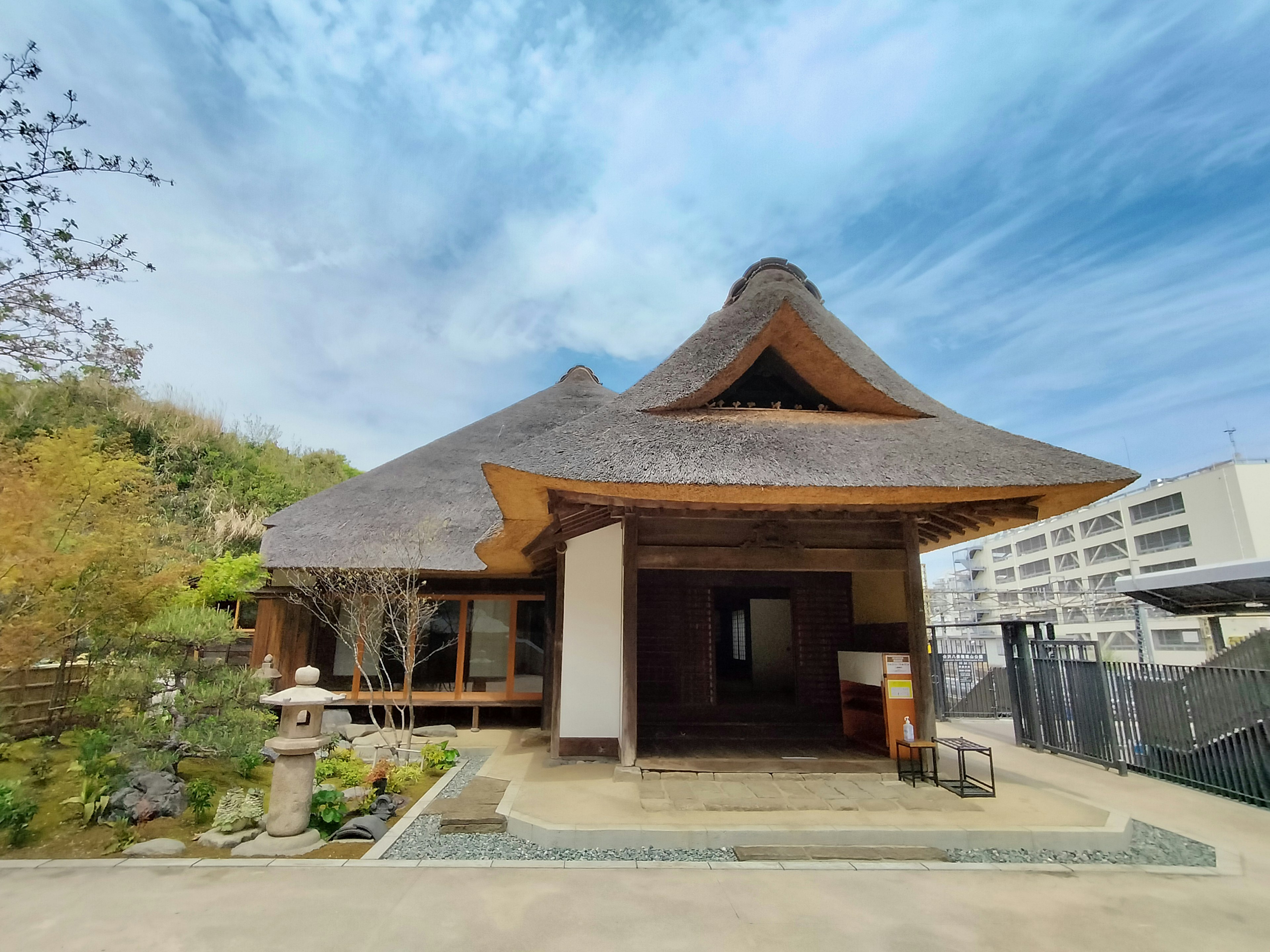 Maison japonaise traditionnelle avec un toit de chaume sous un ciel bleu