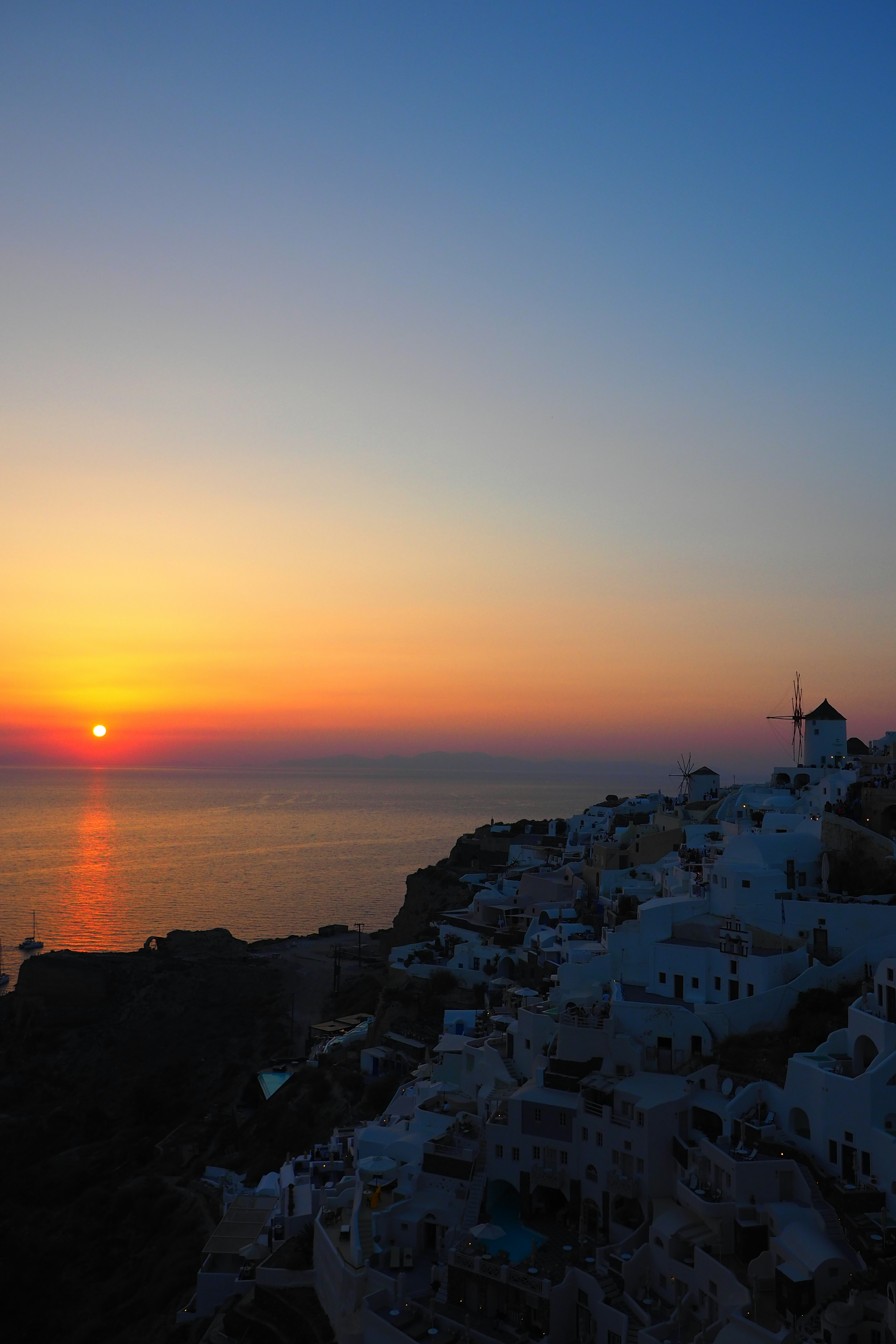 Pemandangan matahari terbenam yang menakjubkan di Santorini bangunan putih di atas bukit