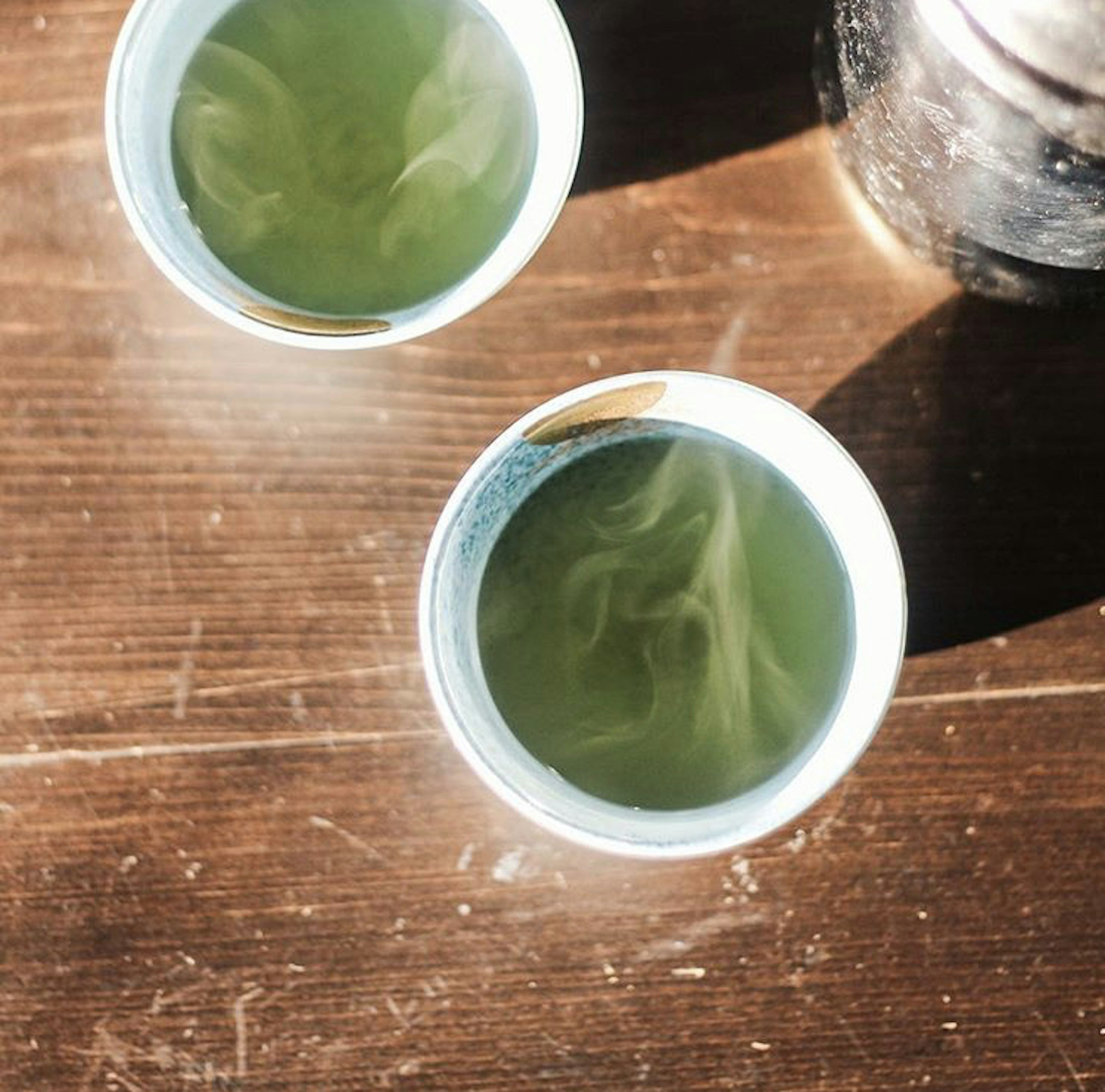 Deux tasses de thé vert fumant sur une table en bois