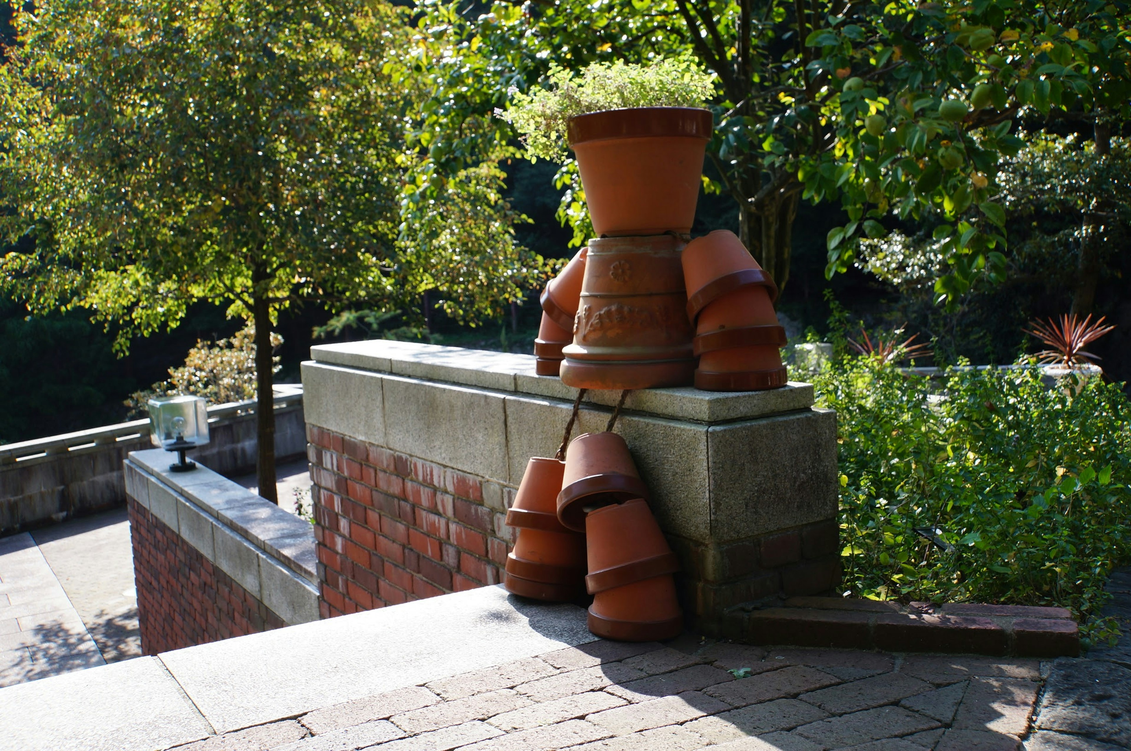 Unique art piece featuring stacked terracotta pots with greenery