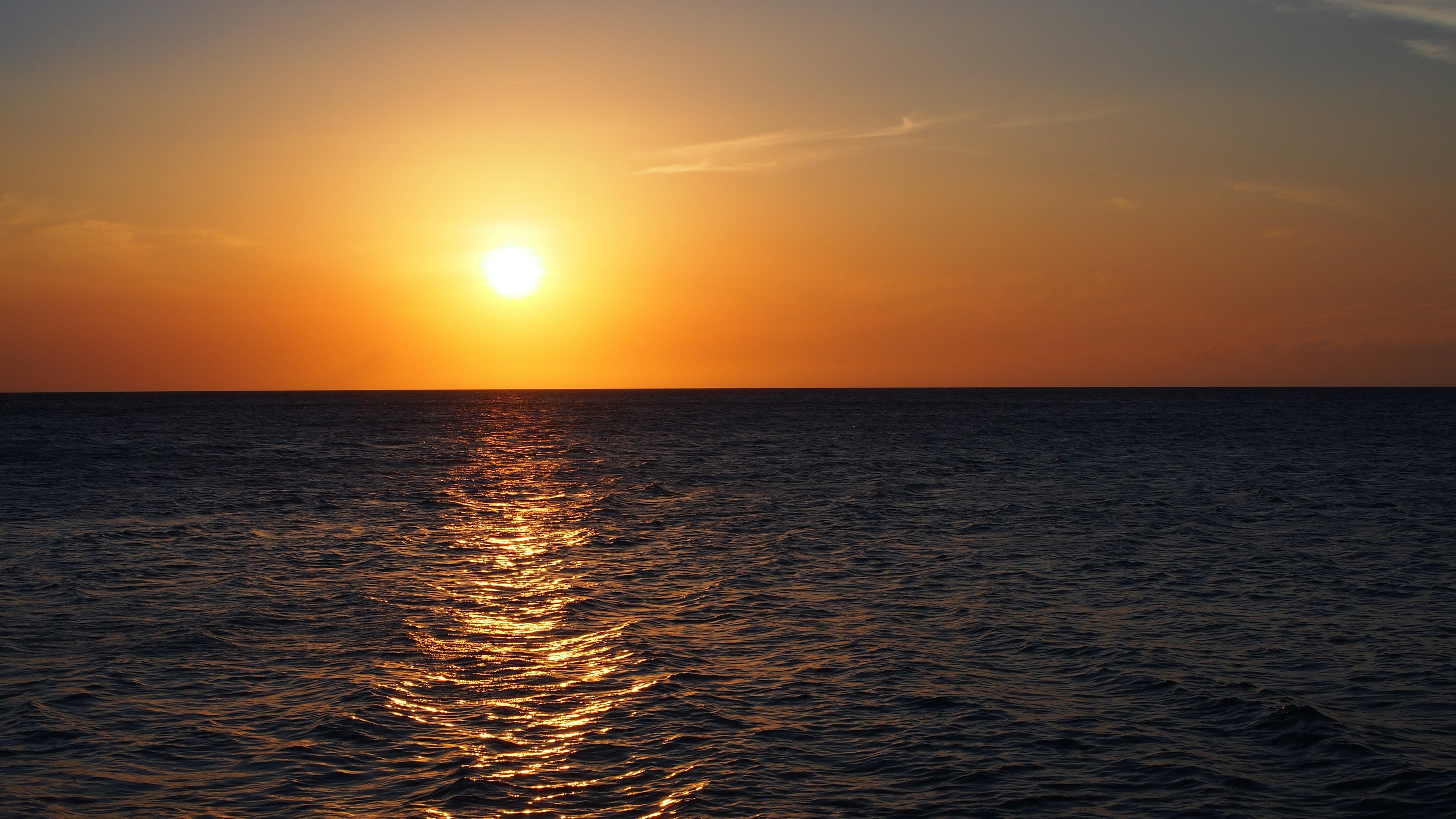 Sol naranja poniéndose sobre aguas oceánicas tranquilas