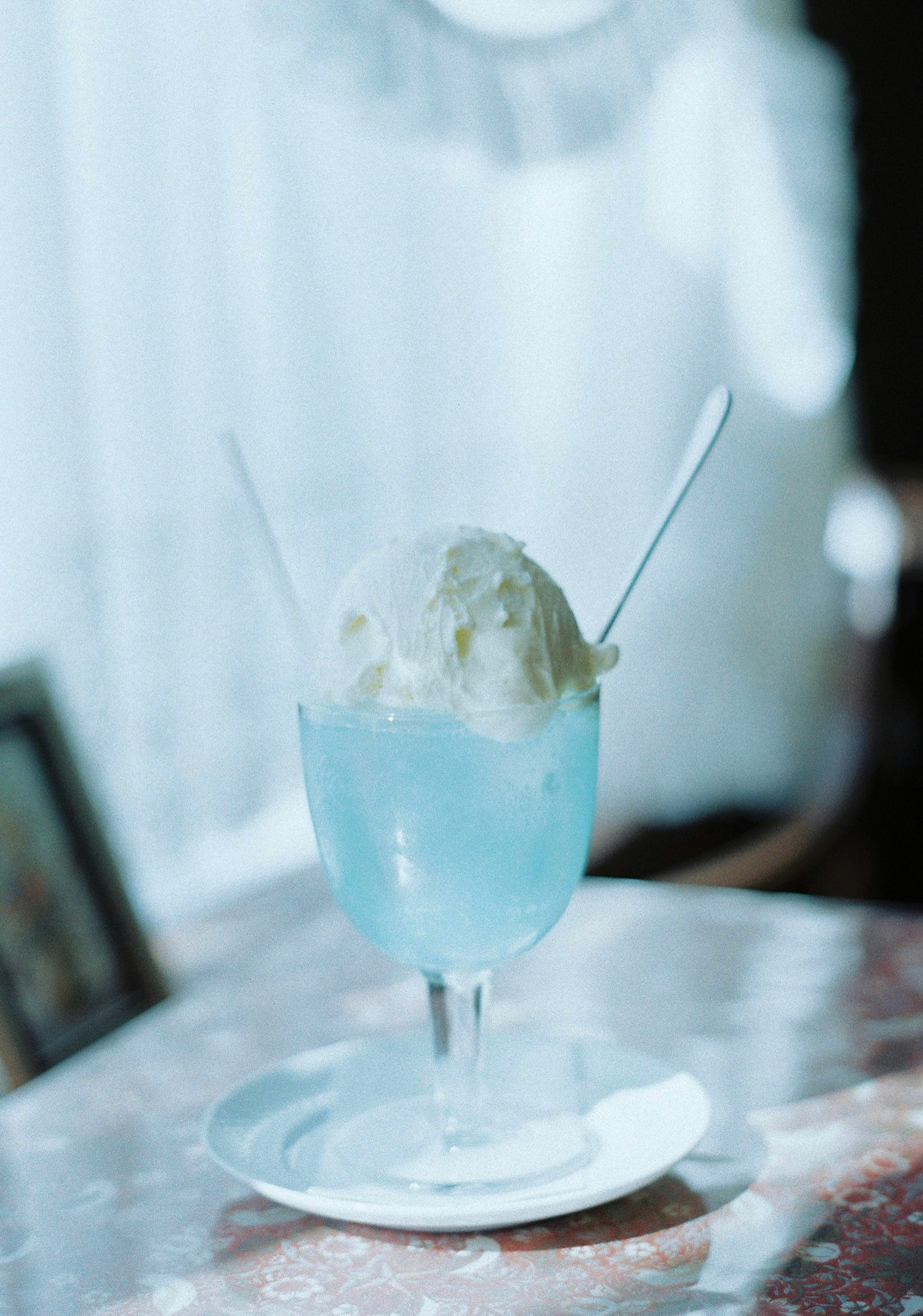 Un verre de boisson bleue surmonté de glace à la vanille et deux cuillères