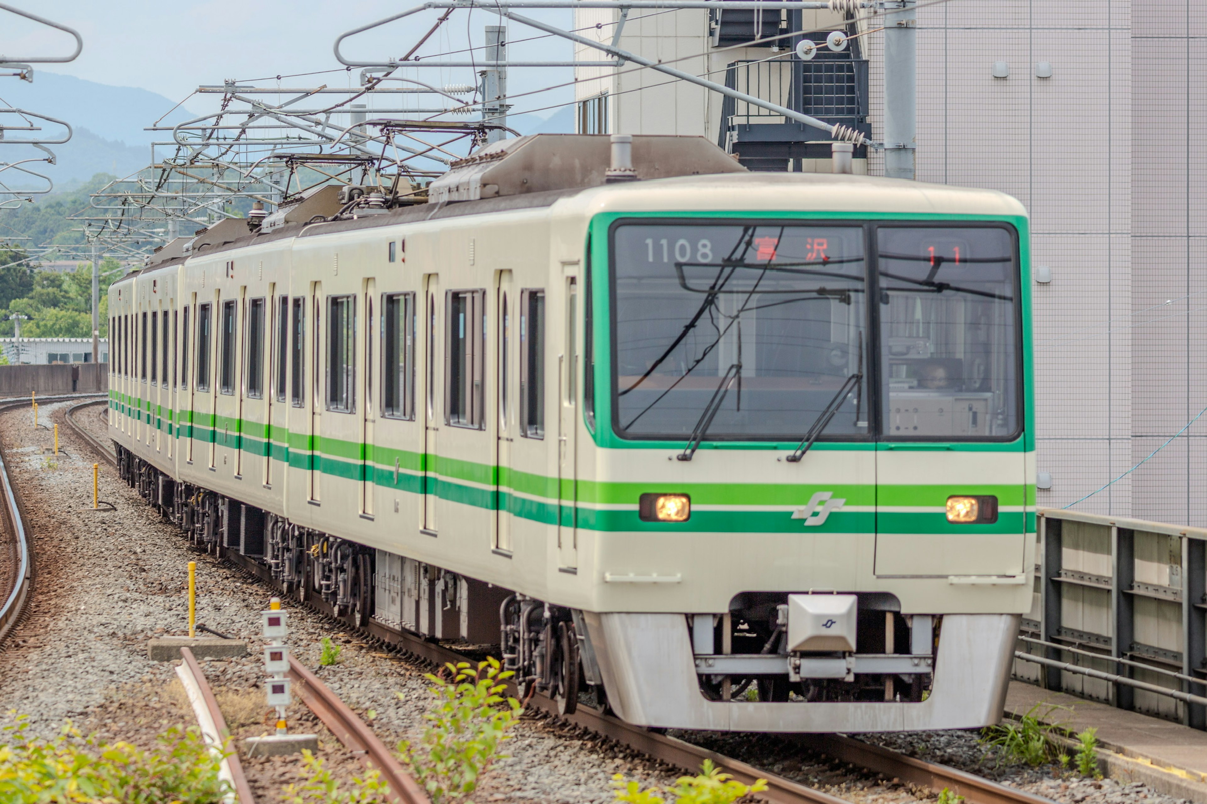 緑のストライプが特徴的な電車が線路を走行中