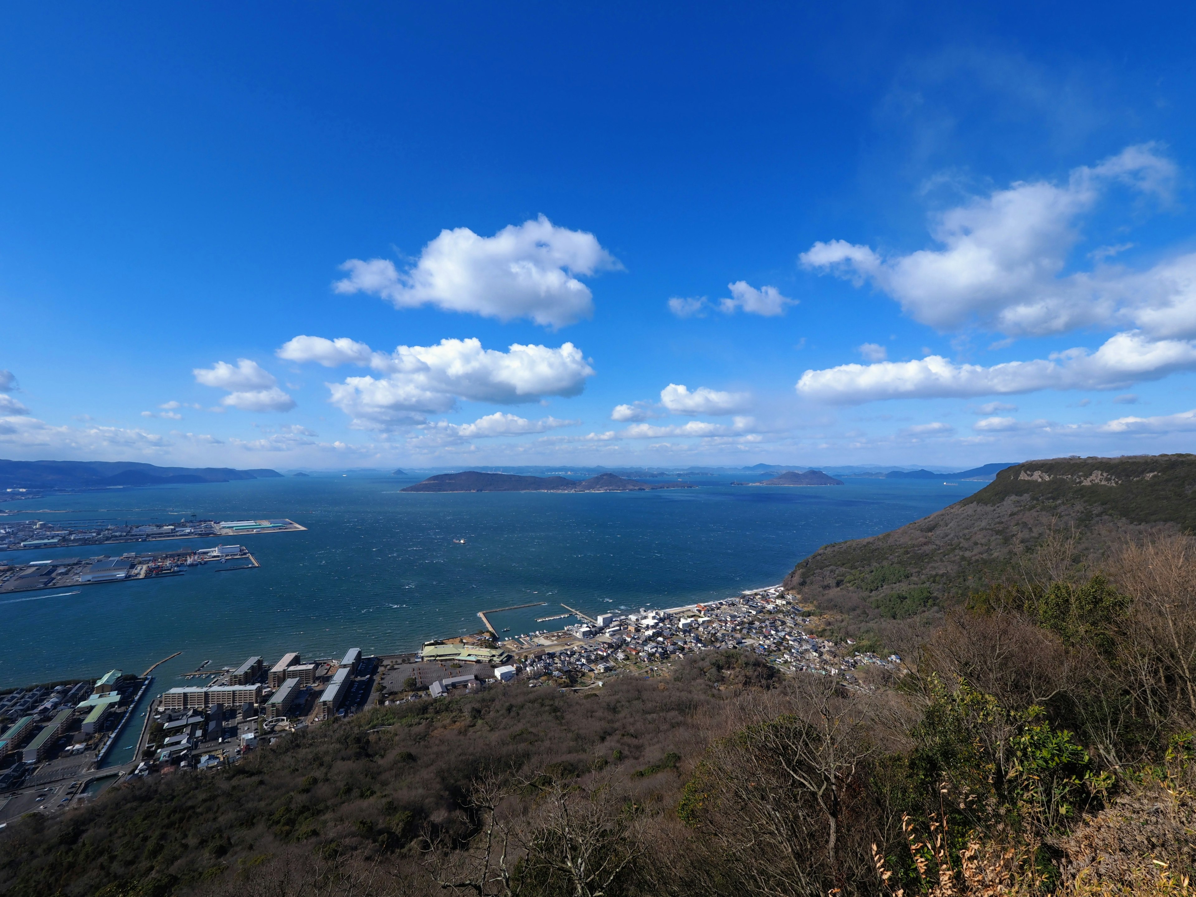 Vue panoramique d'une ville portuaire avec ciel bleu et nuages blancs sur la mer