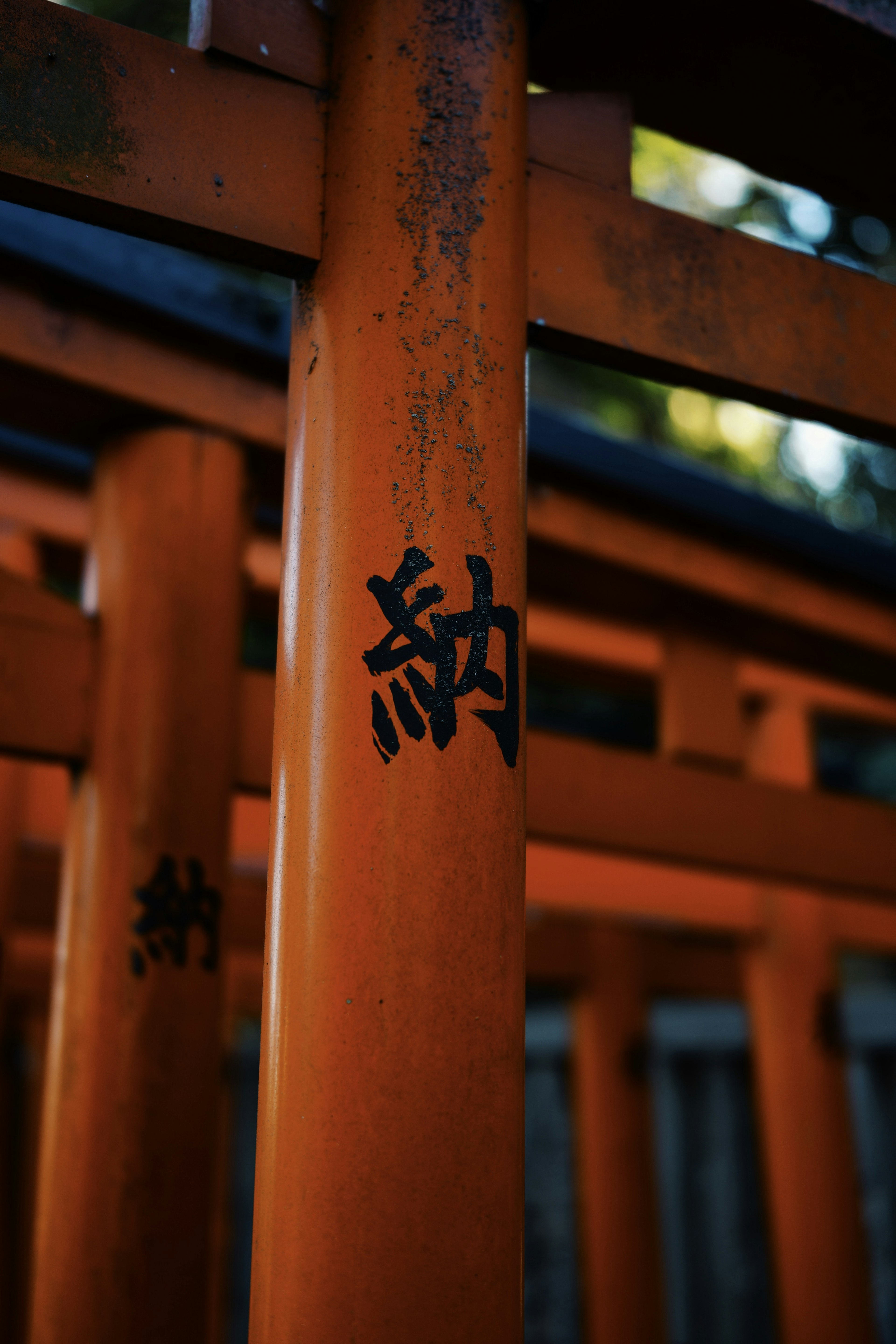 Primo piano di un palo di torii arancione con iscrizioni in kanji nero