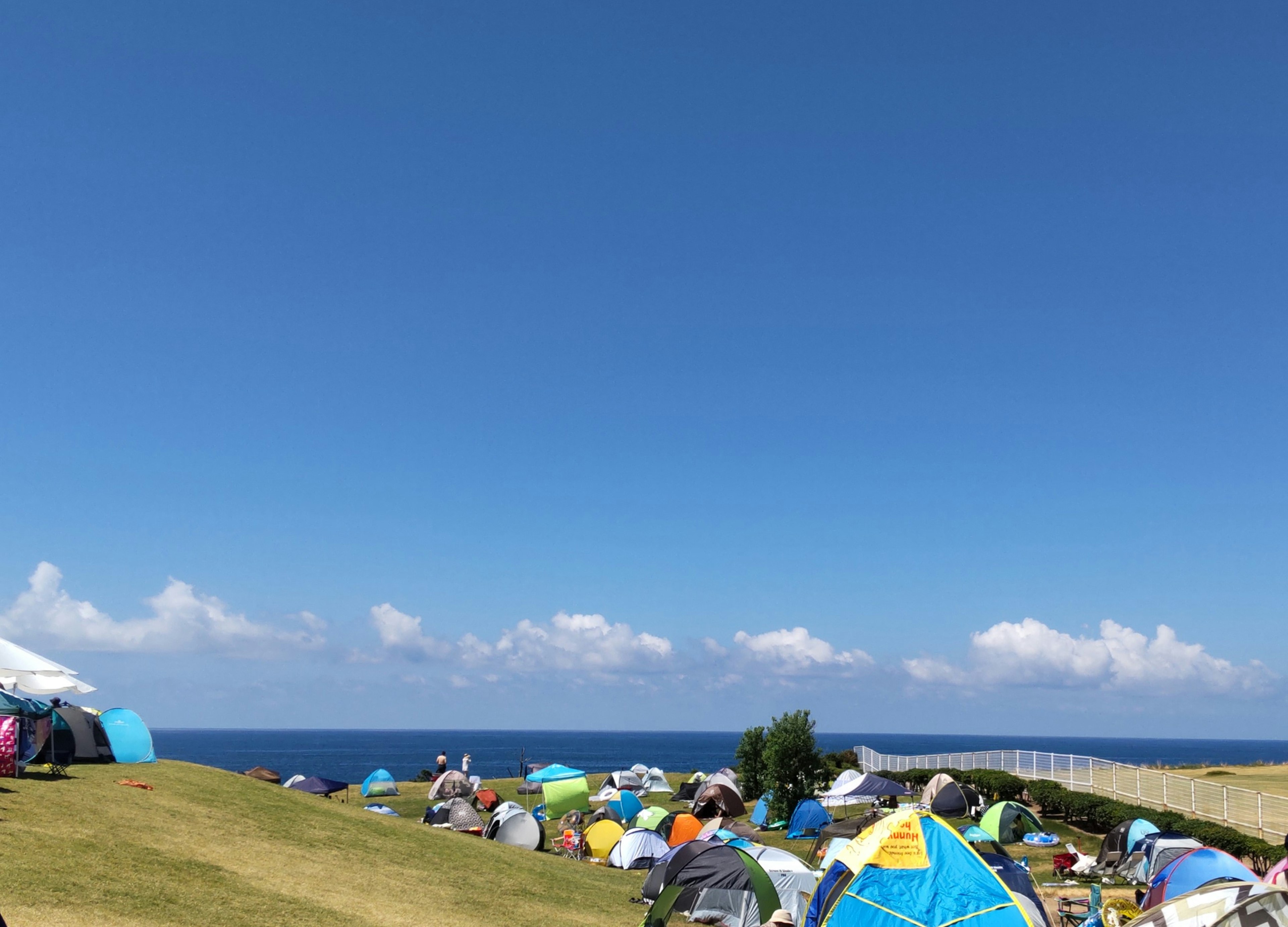 Una scena di campeggio con tende colorate sotto un cielo blu