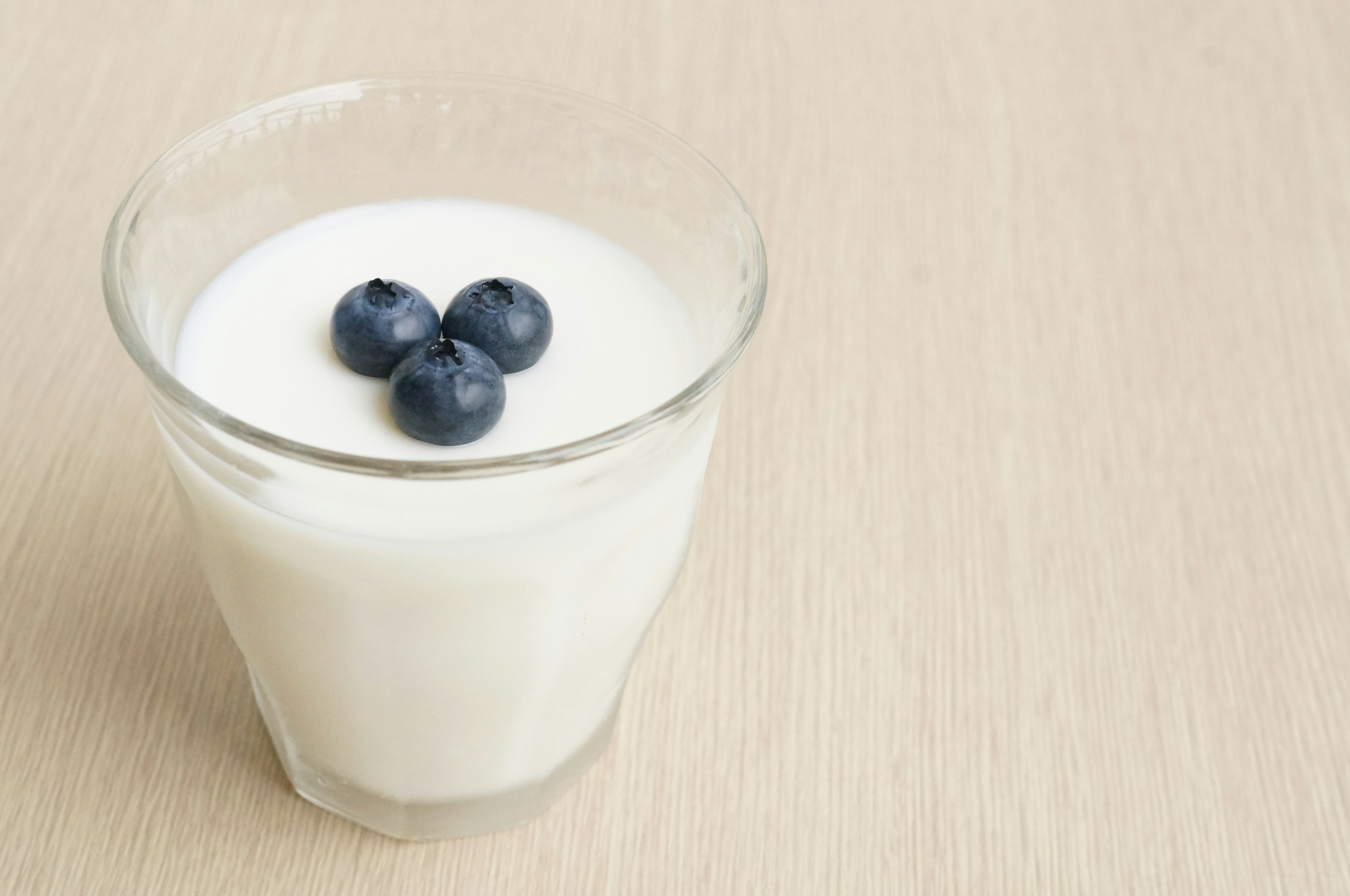 A glass of yogurt topped with three blueberries