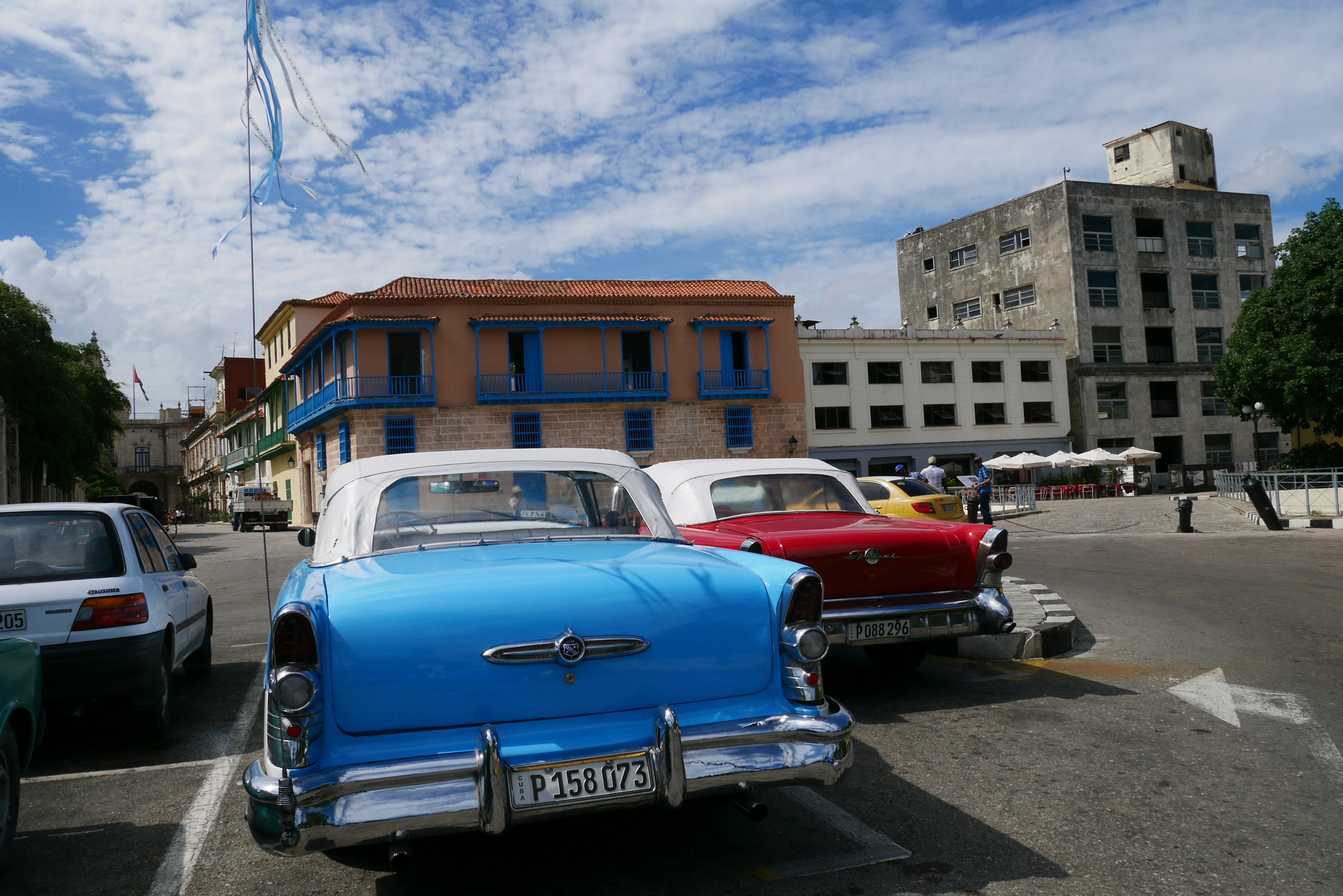 Coche clásico azul y coche clásico rojo estacionados en una escena urbana