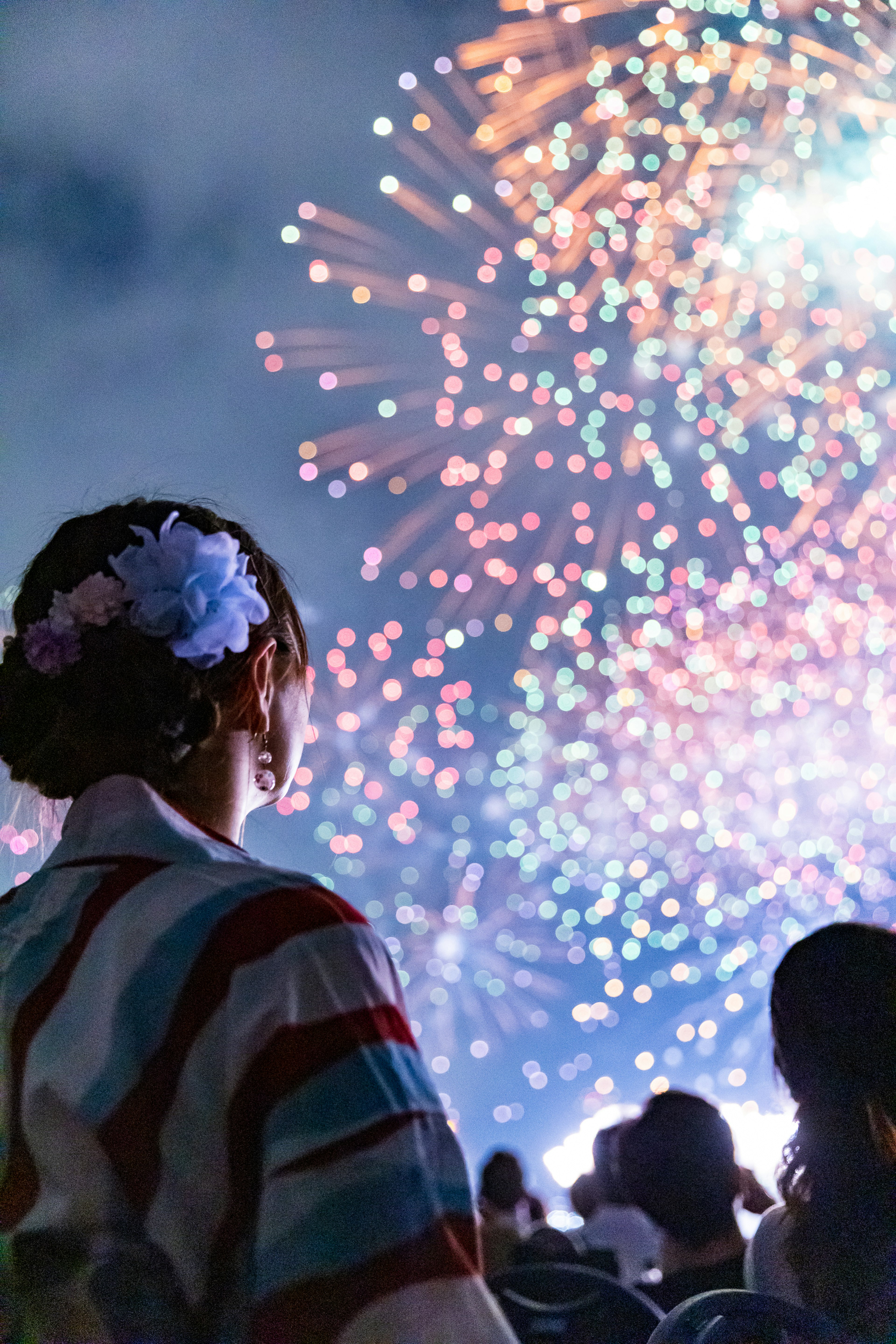 Mujer en kimono viendo un espectáculo de fuegos artificiales coloridos