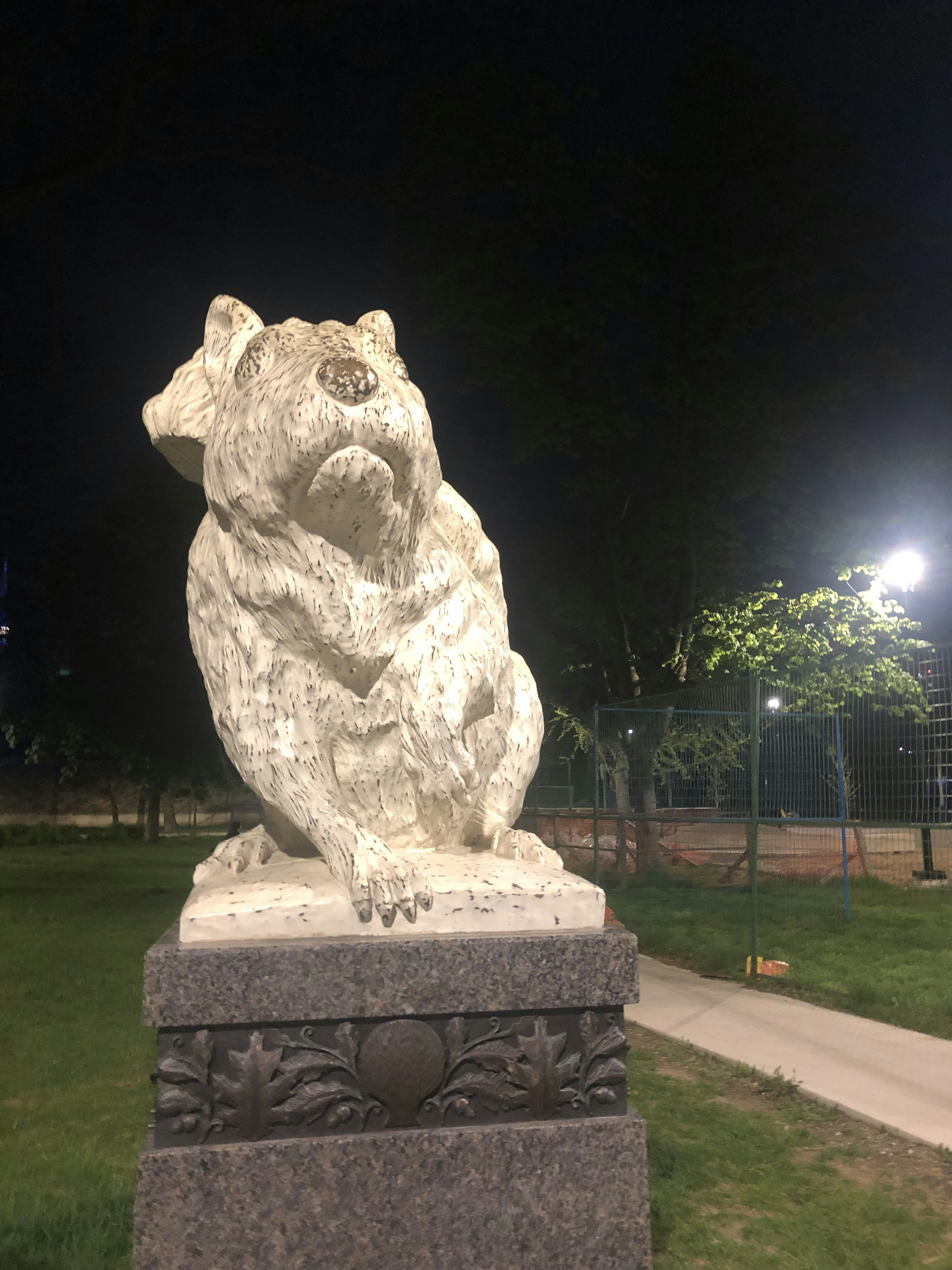 Stone animal sculpture in a park at night appearing in a sitting posture