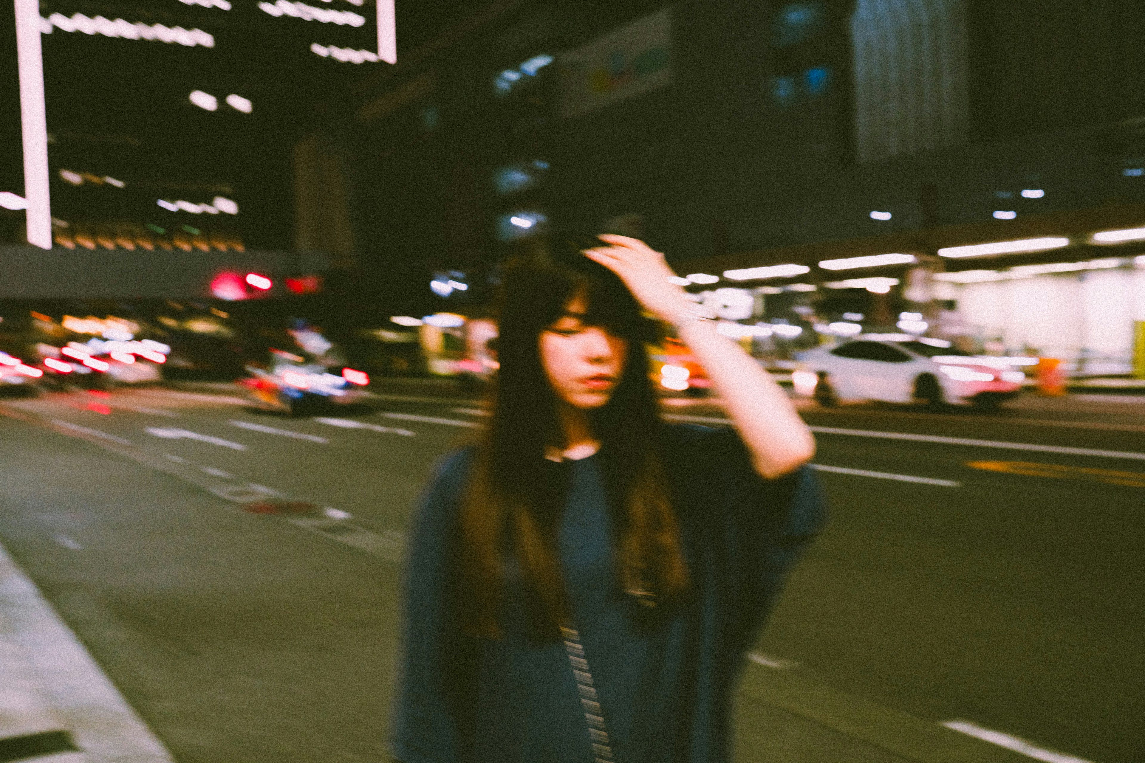 A woman touching her hair on a city street at night