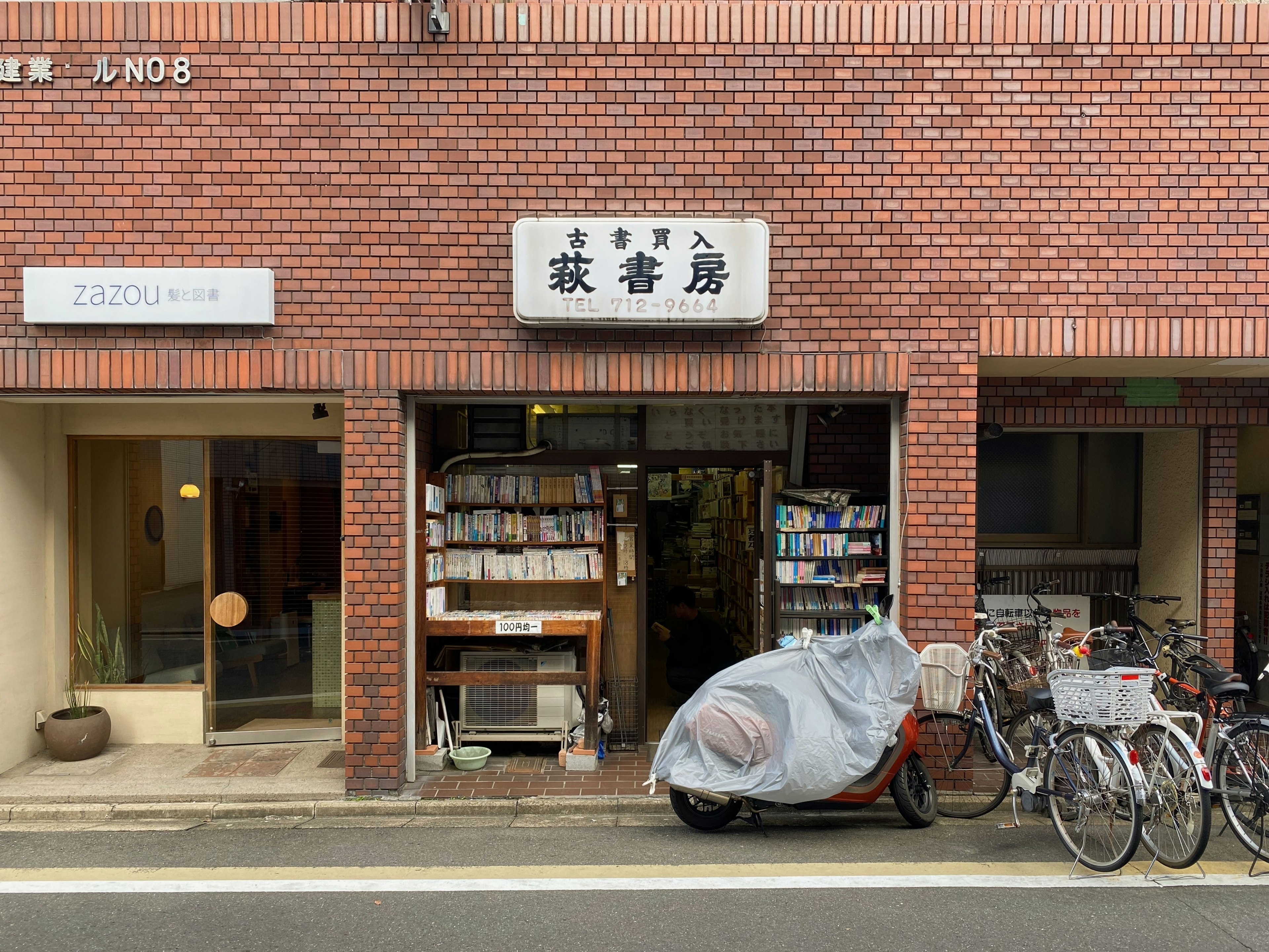 Façade d'une librairie d'occasion dans un bâtiment en briques avec des vélos alignés à l'extérieur