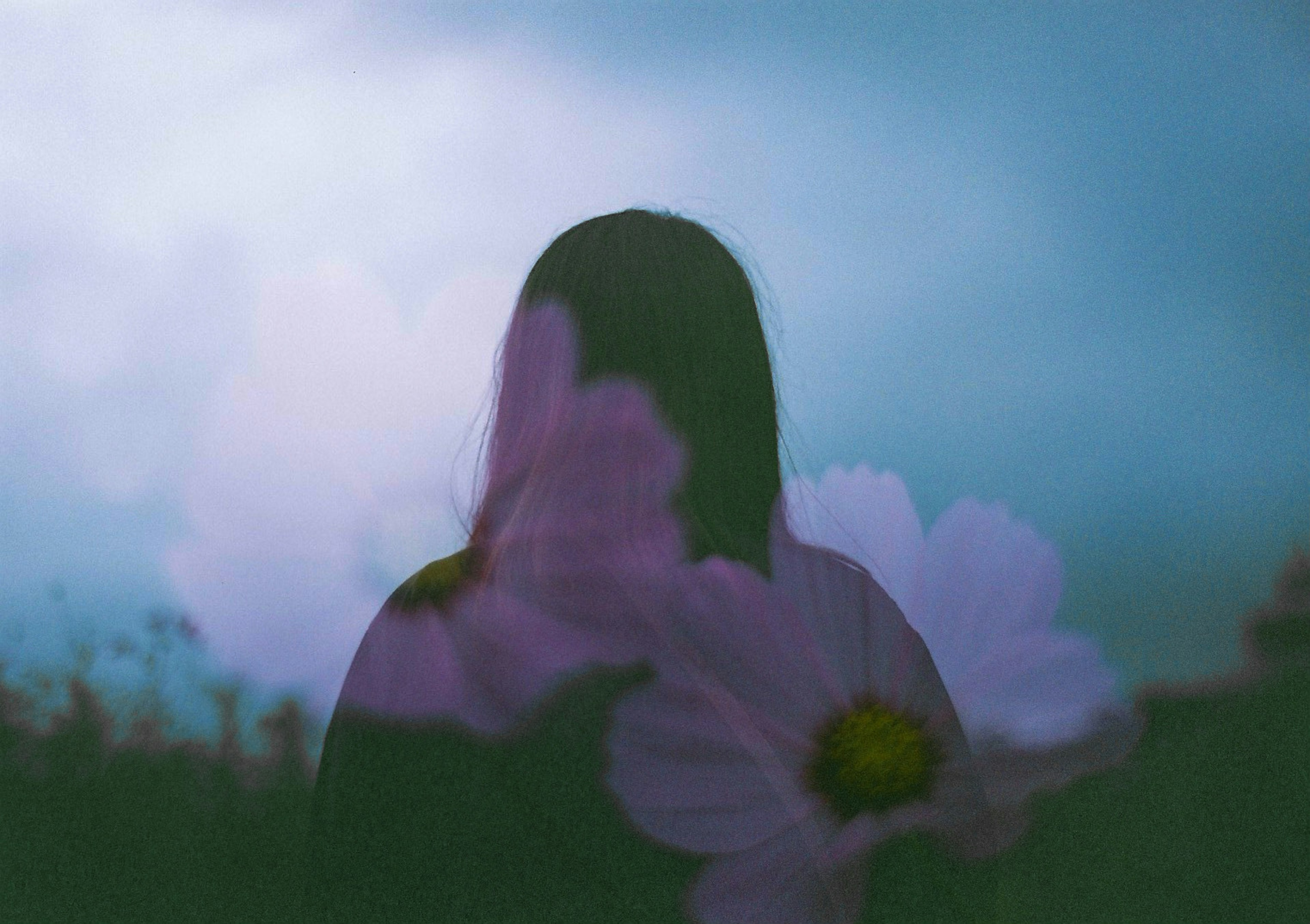 Ein traumhaftes Bild mit der Silhouette einer Frau, die mit Blumen vor einem sanften Hintergrund überlagert ist