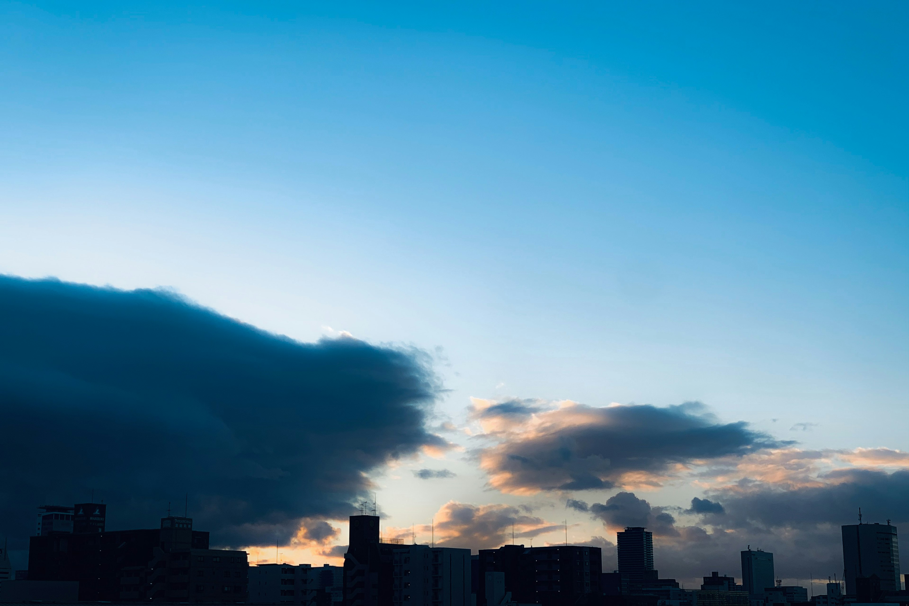 青空と雲が広がる美しい夕暮れの都市のシルエット