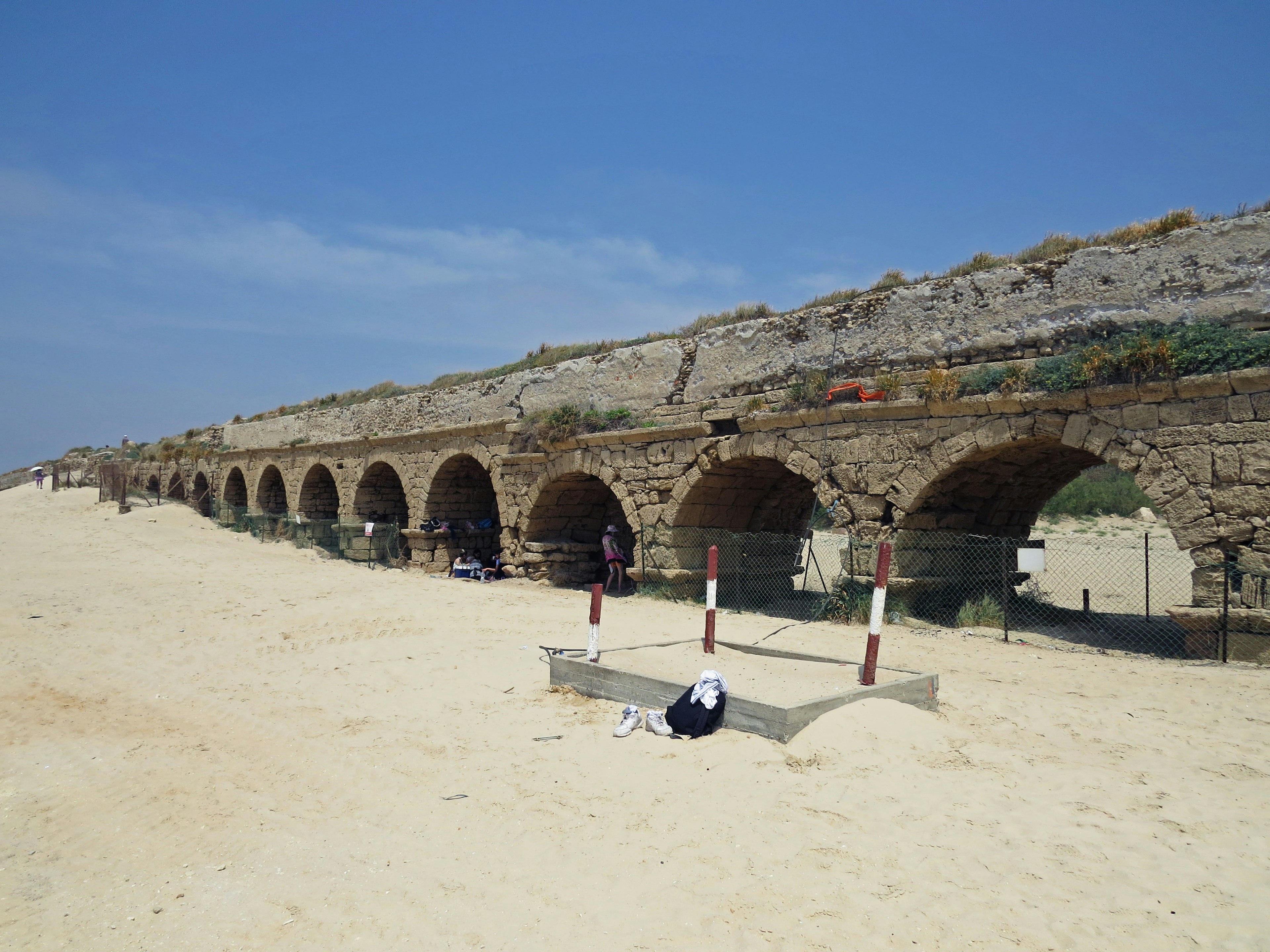 Antike Aquädukt-Ruinen an einem Sandstrand unter einem blauen Himmel