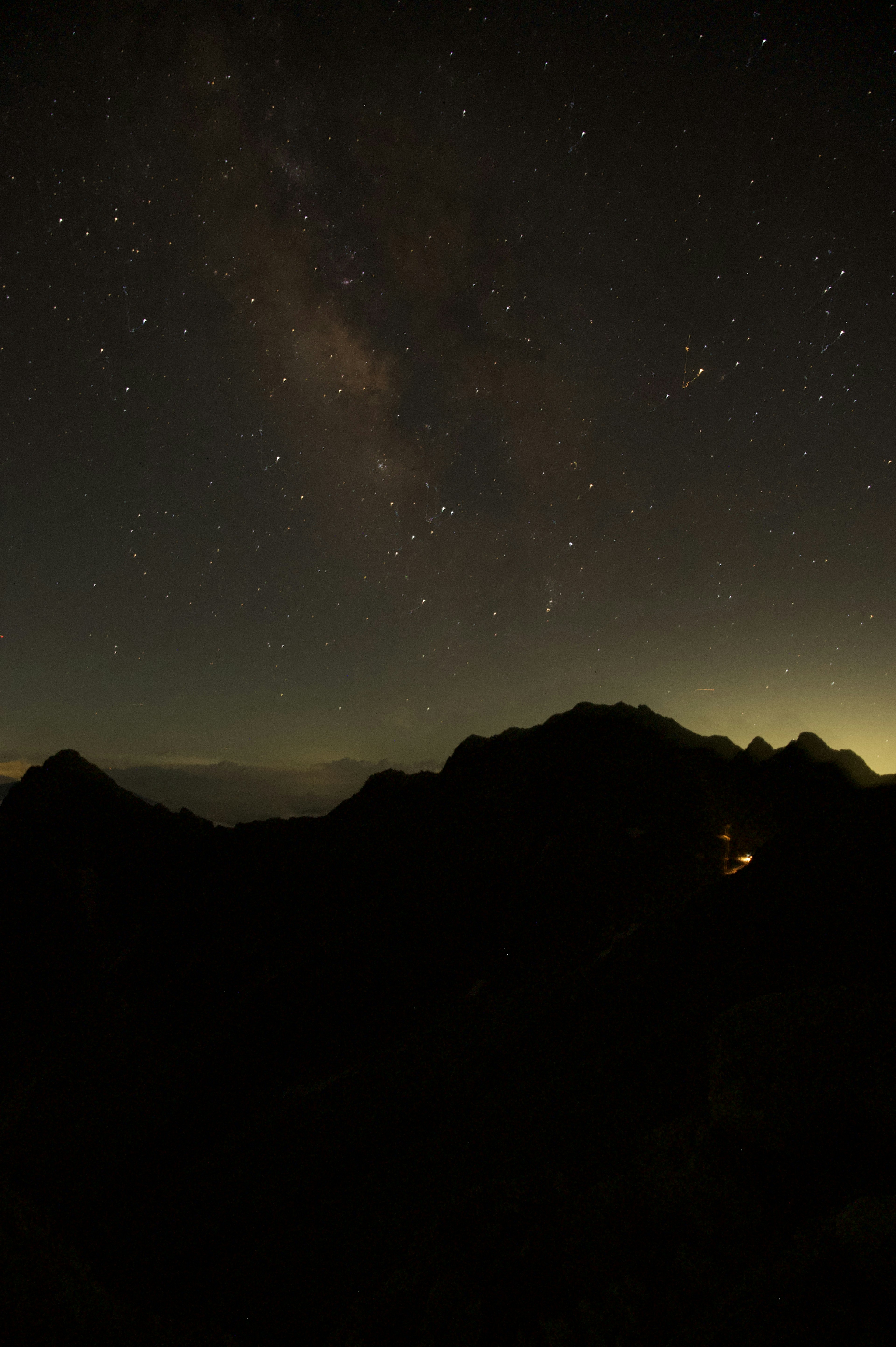 Paesaggio notturno con cielo stellato e silhouette di montagne