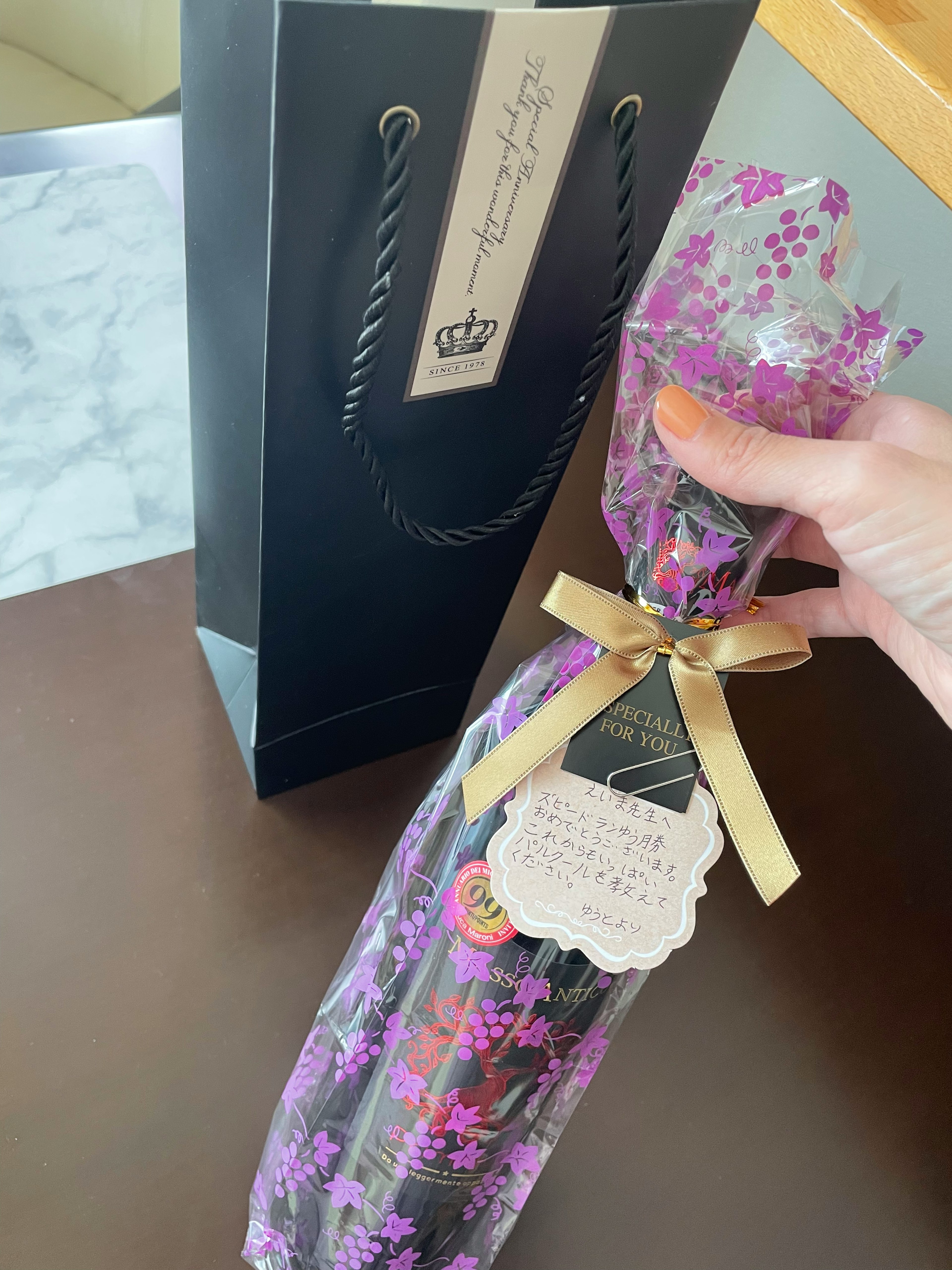 Flasche, eingewickelt in lila Blumen, mit einer schwarzen Geschenkverpackung