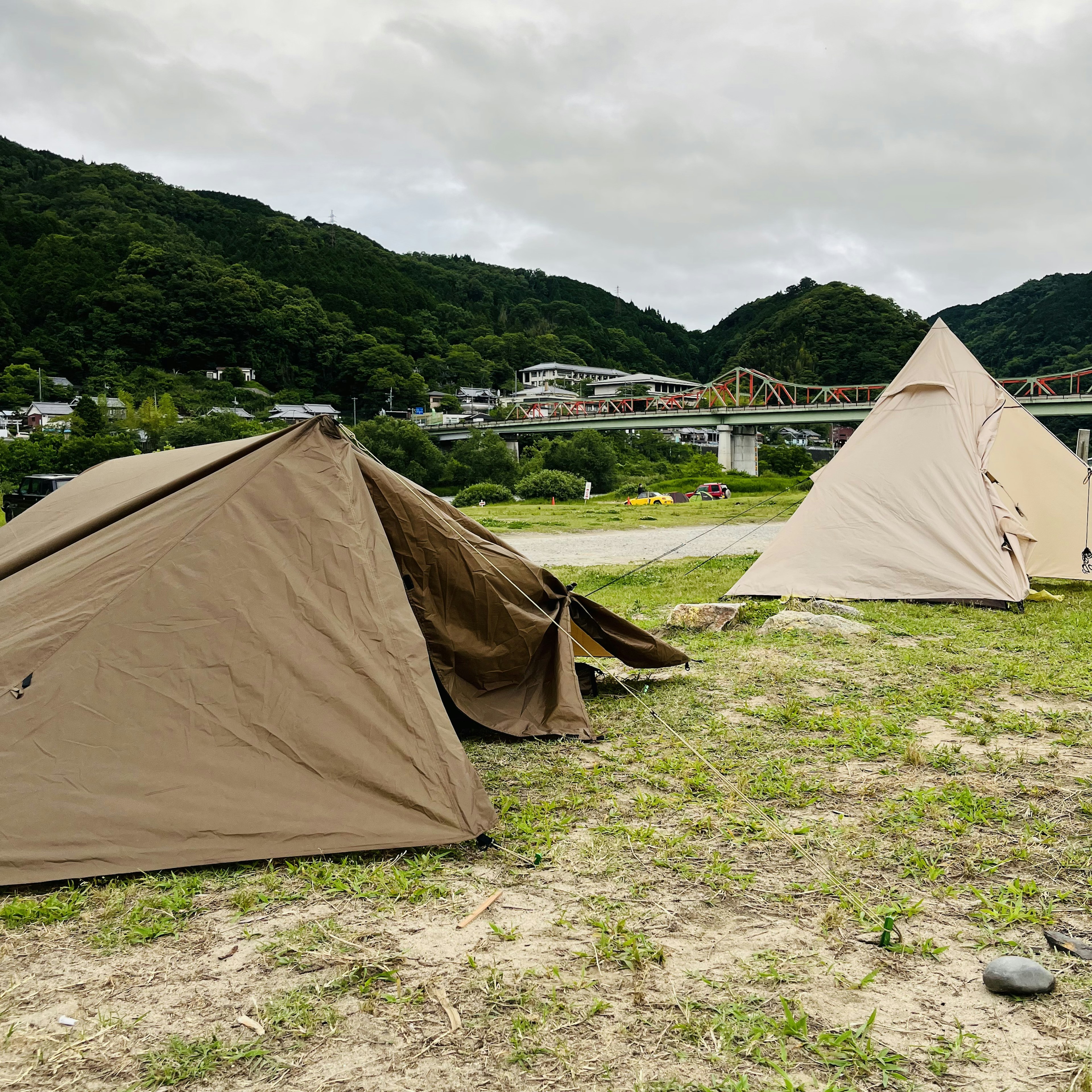 川の近くにある茶色のテントが二つ並んでいる風景