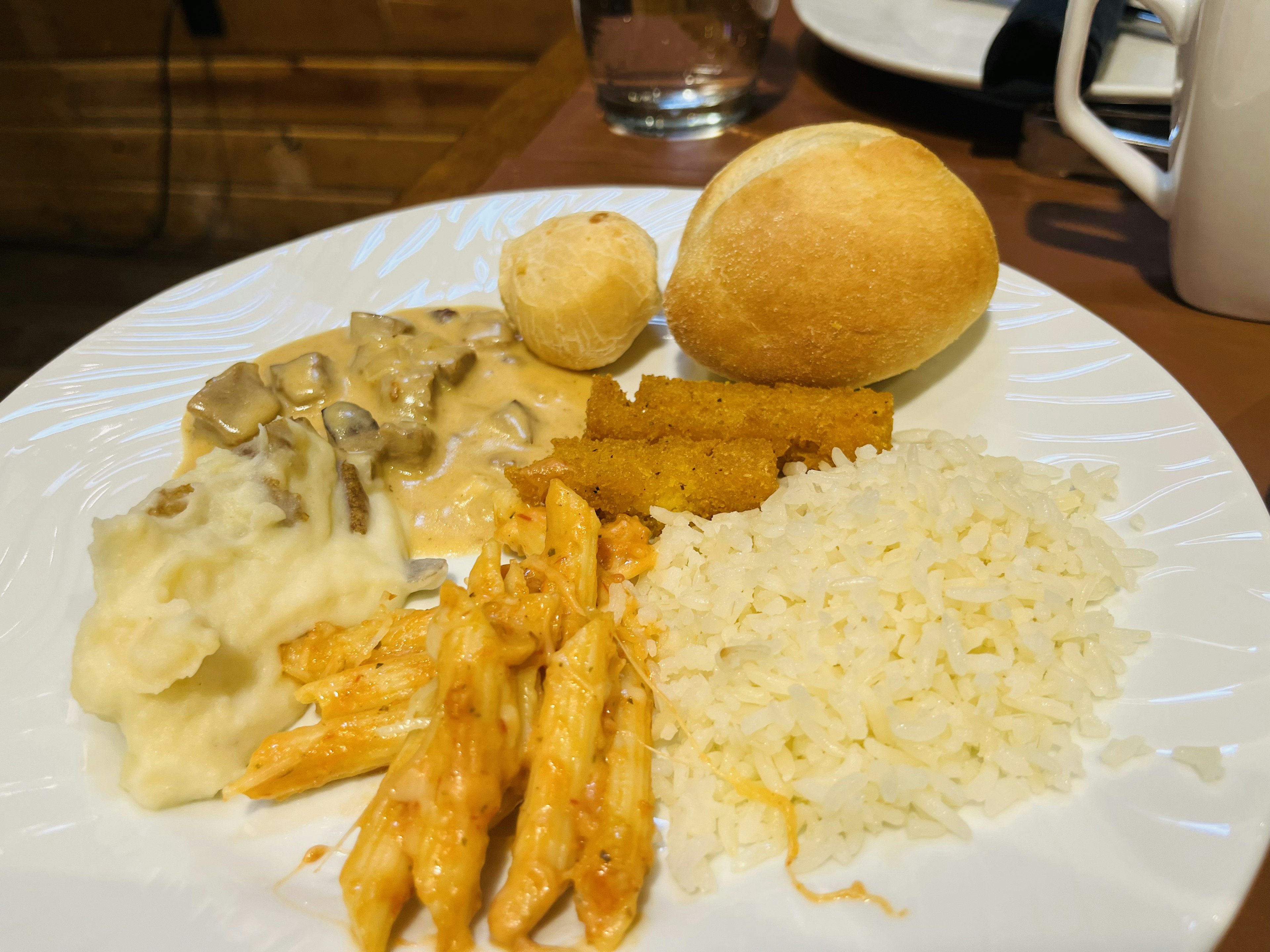 Une assiette remplie de divers plats incluant du riz, des crevettes et un petit pain