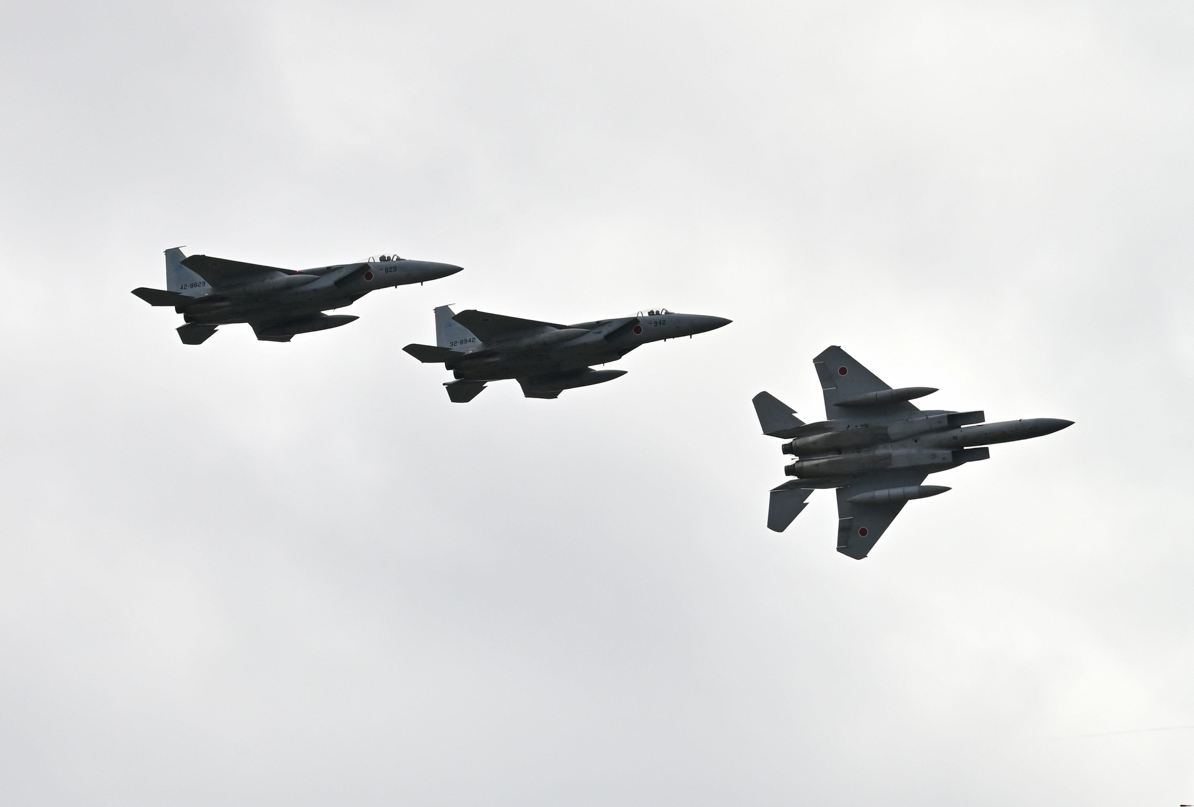 Three fighter jets flying in formation against a cloudy sky