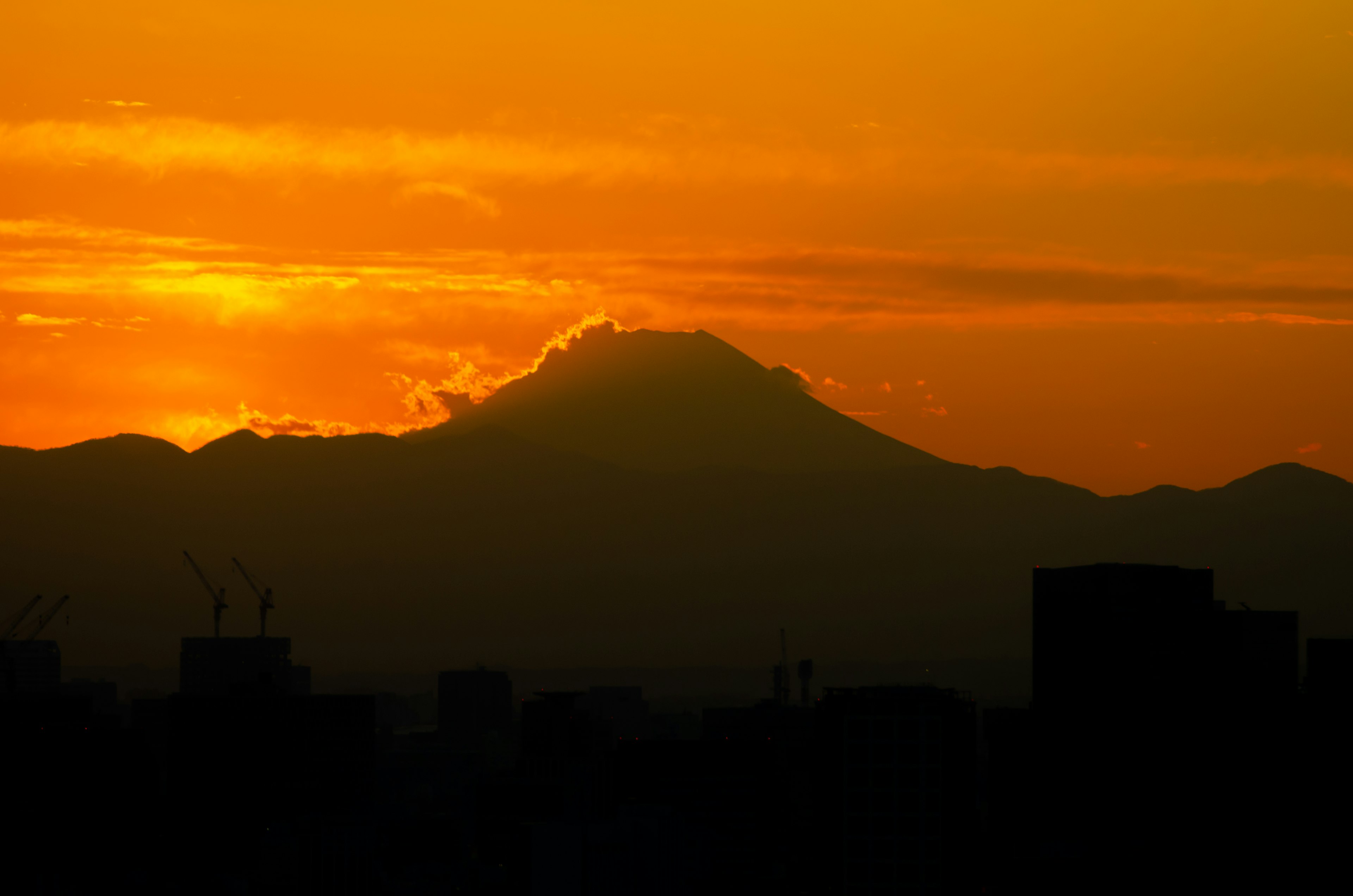 Silhouette eines Berges vor einem orangefarbenen Sonnenuntergangshimmel