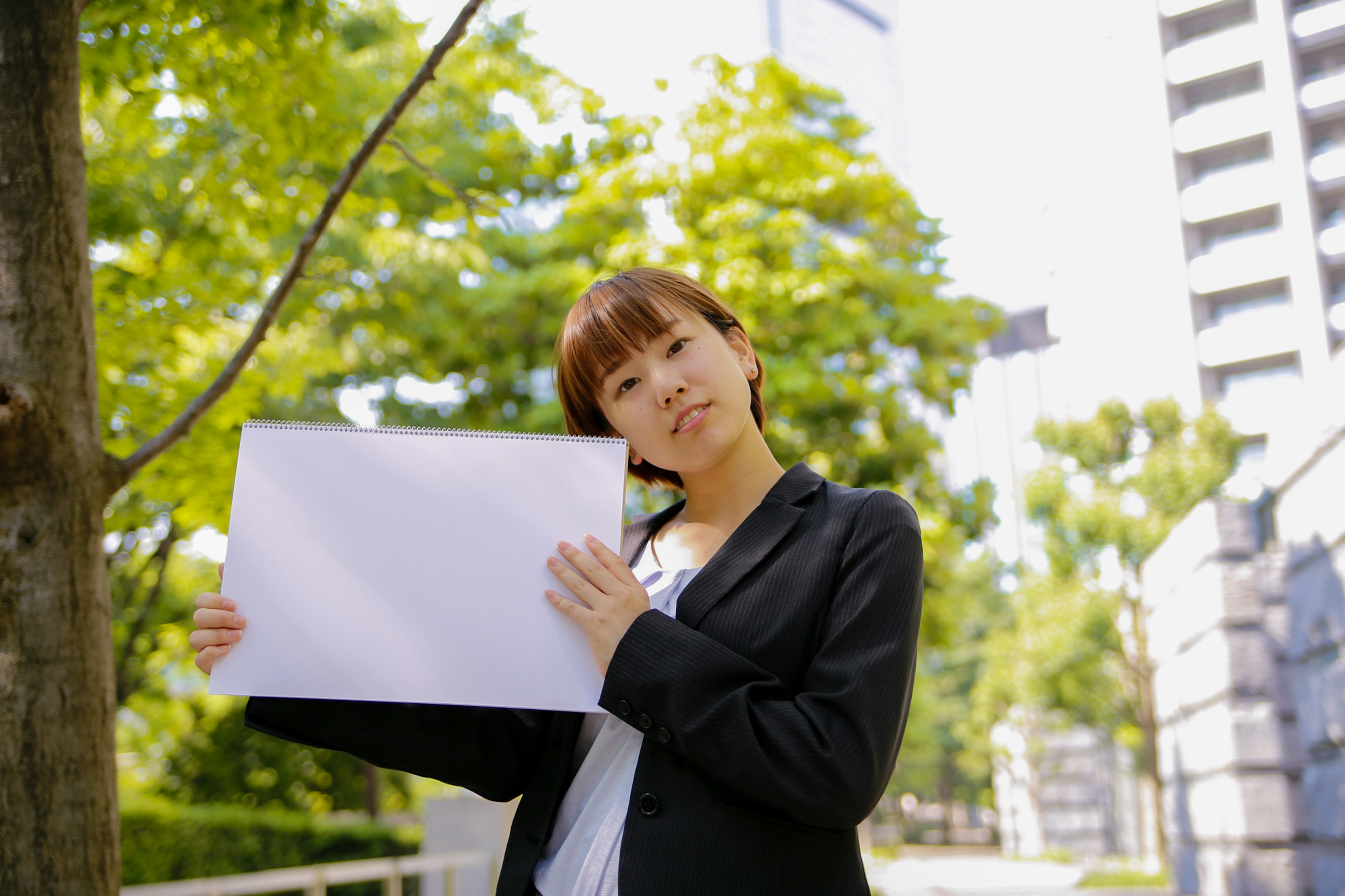 Femme en tenue professionnelle tenant une feuille blanche à l'extérieur