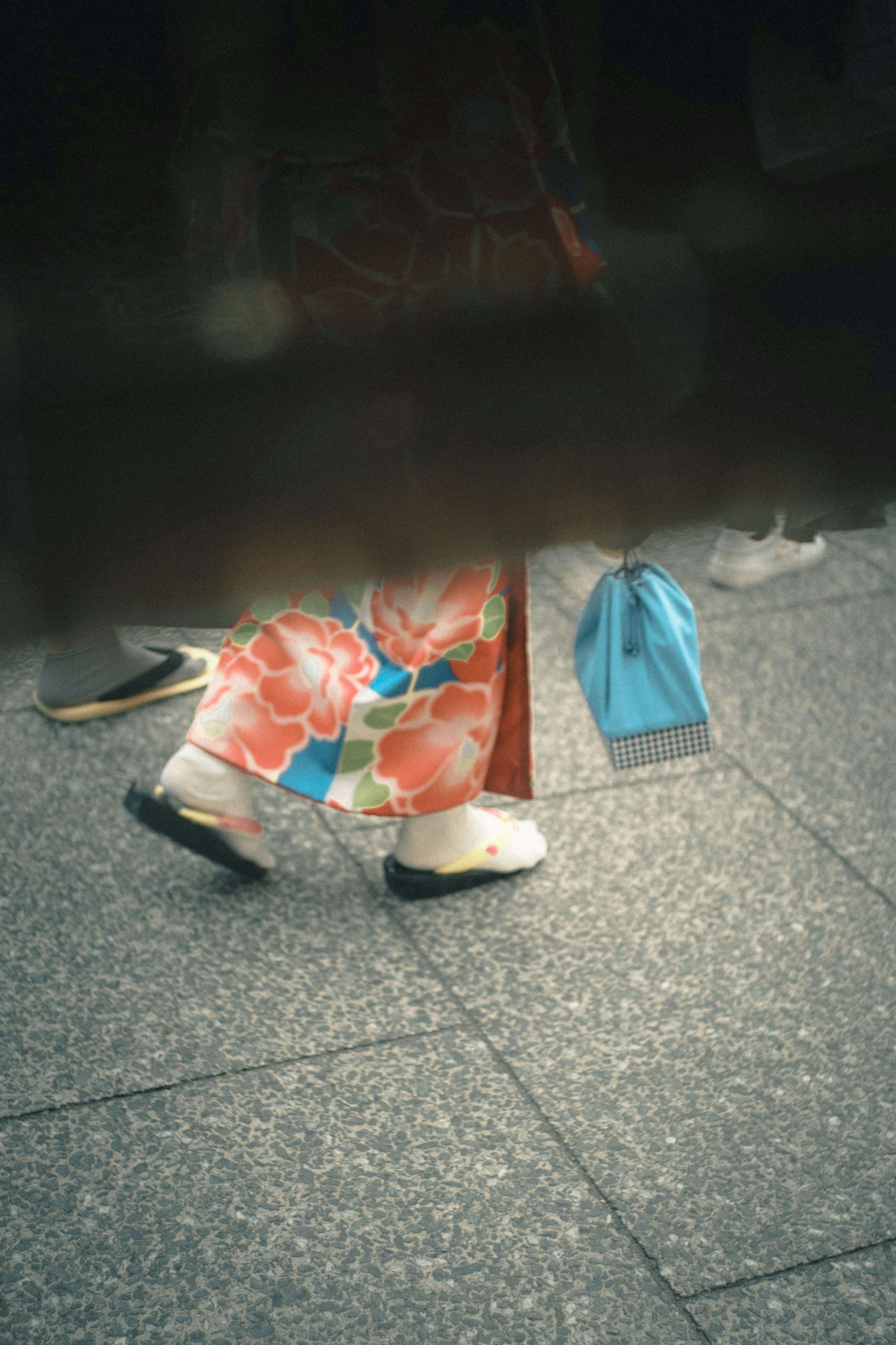 Füße einer Person in einem bunten Blumen-Kimono auf einem Steinboden