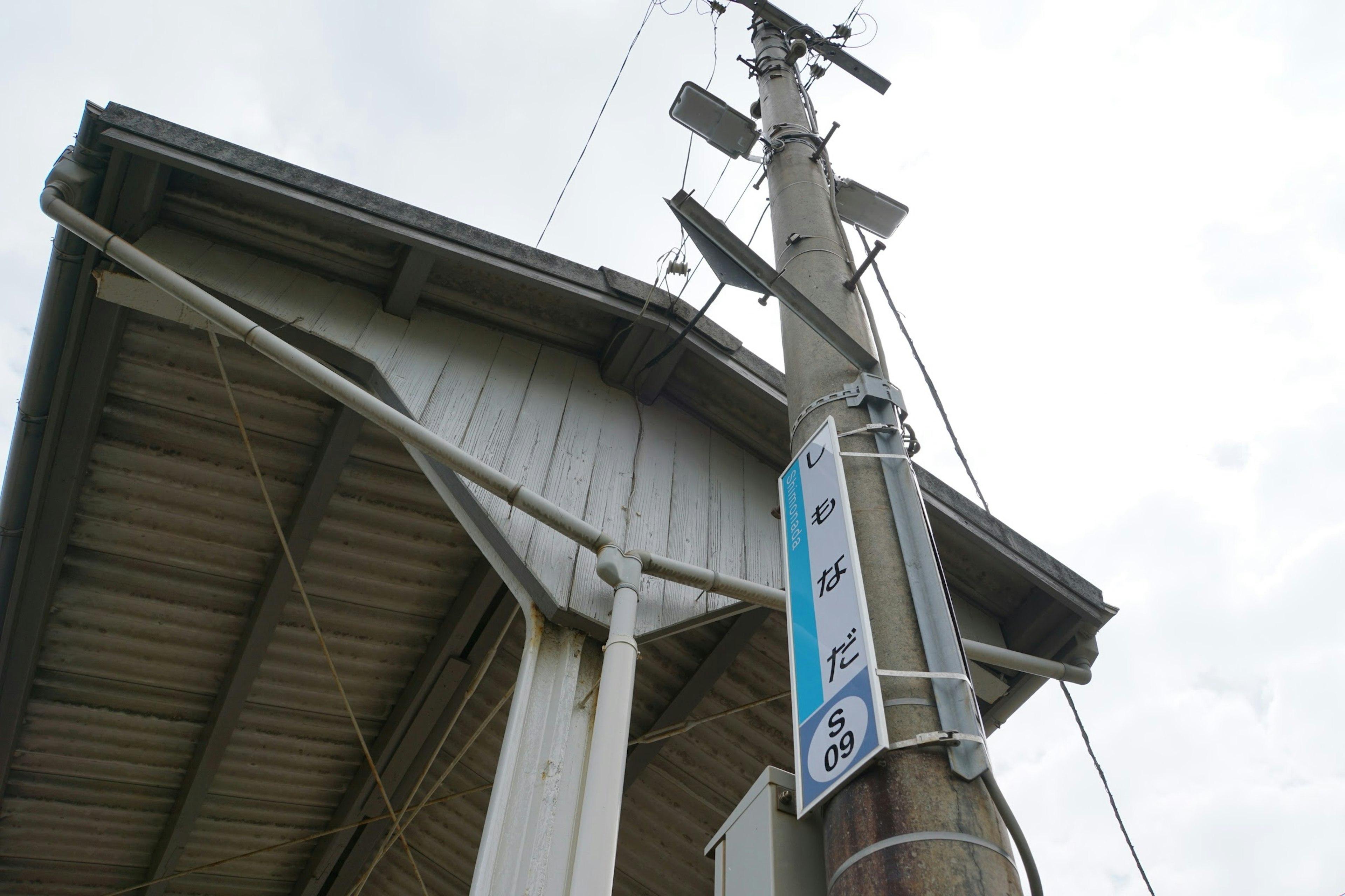 Photo looking up at a power pole and part of a house roof