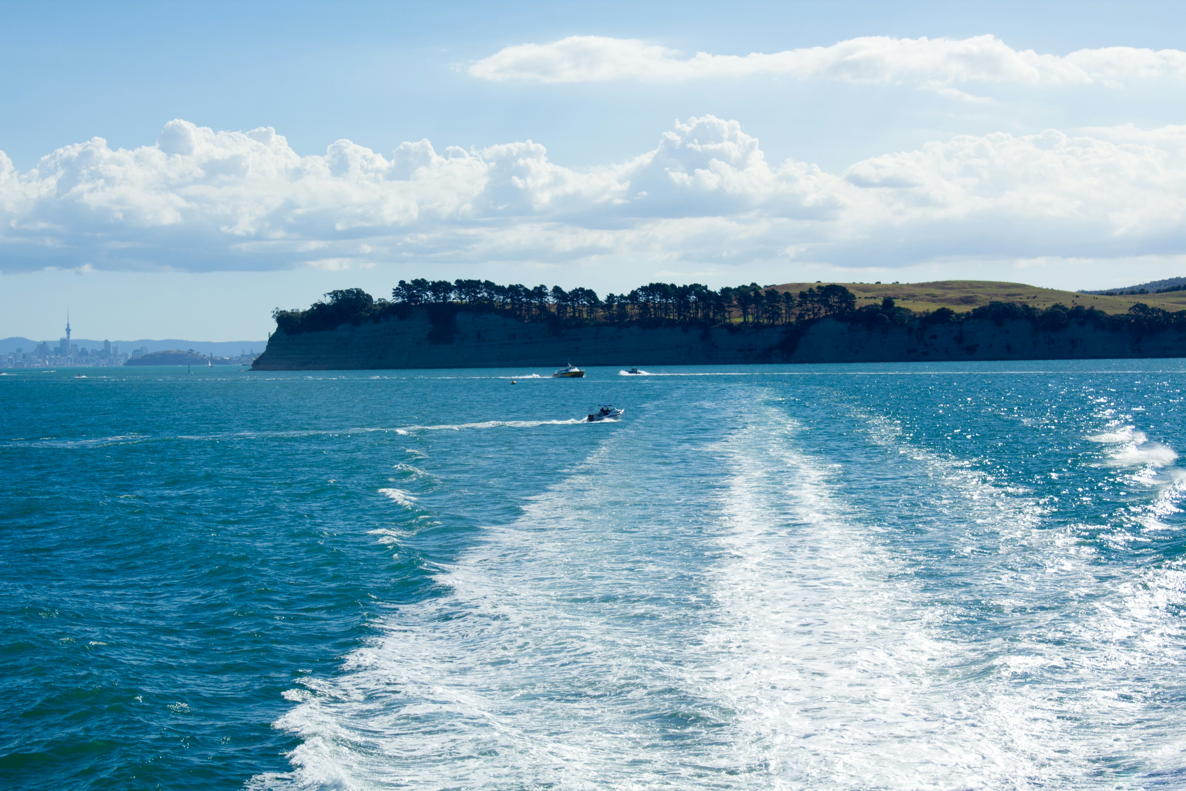 A scenic view of blue water with boat trails under a clear sky