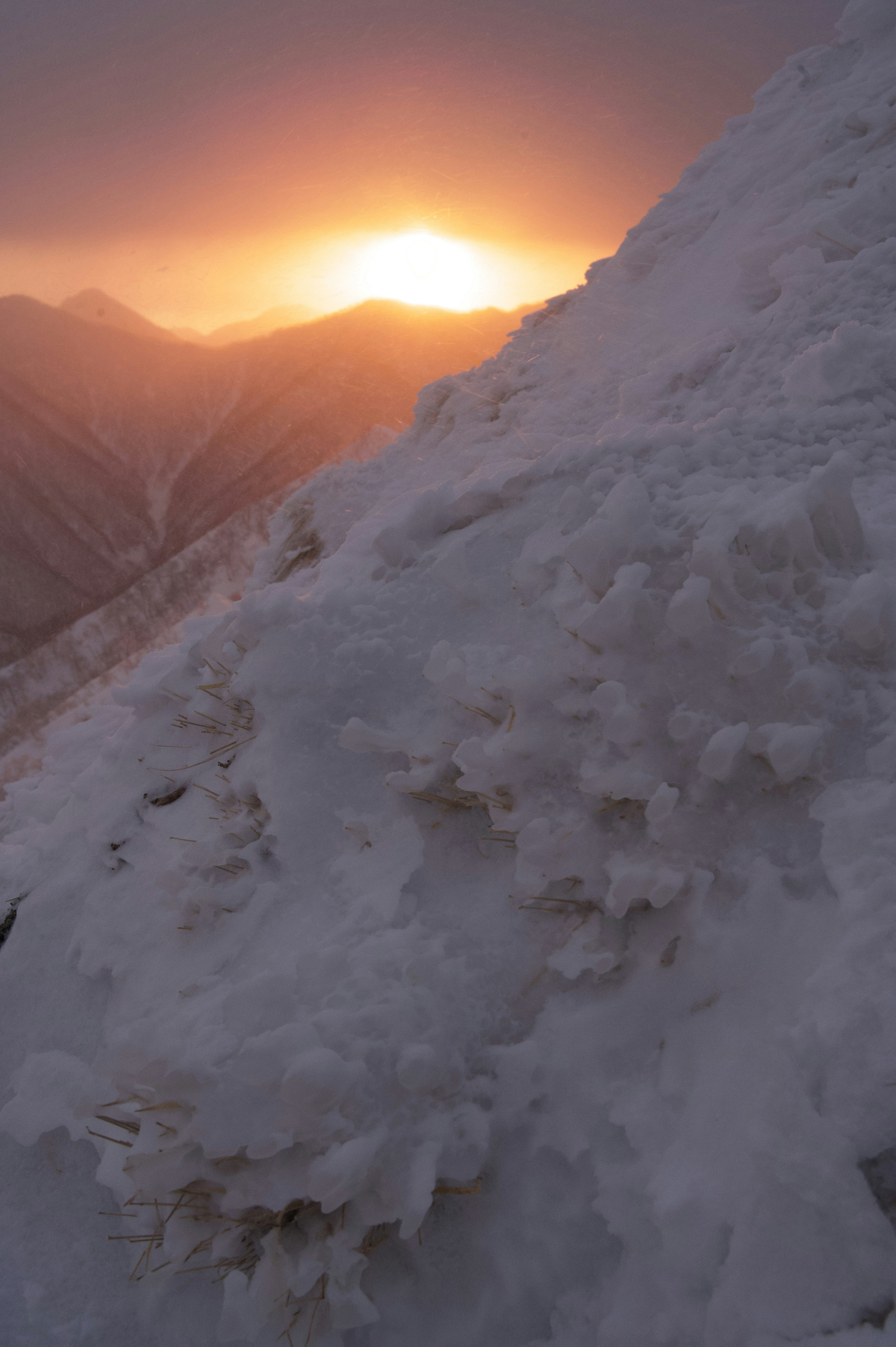 Snow-covered mountain slope with a sunset