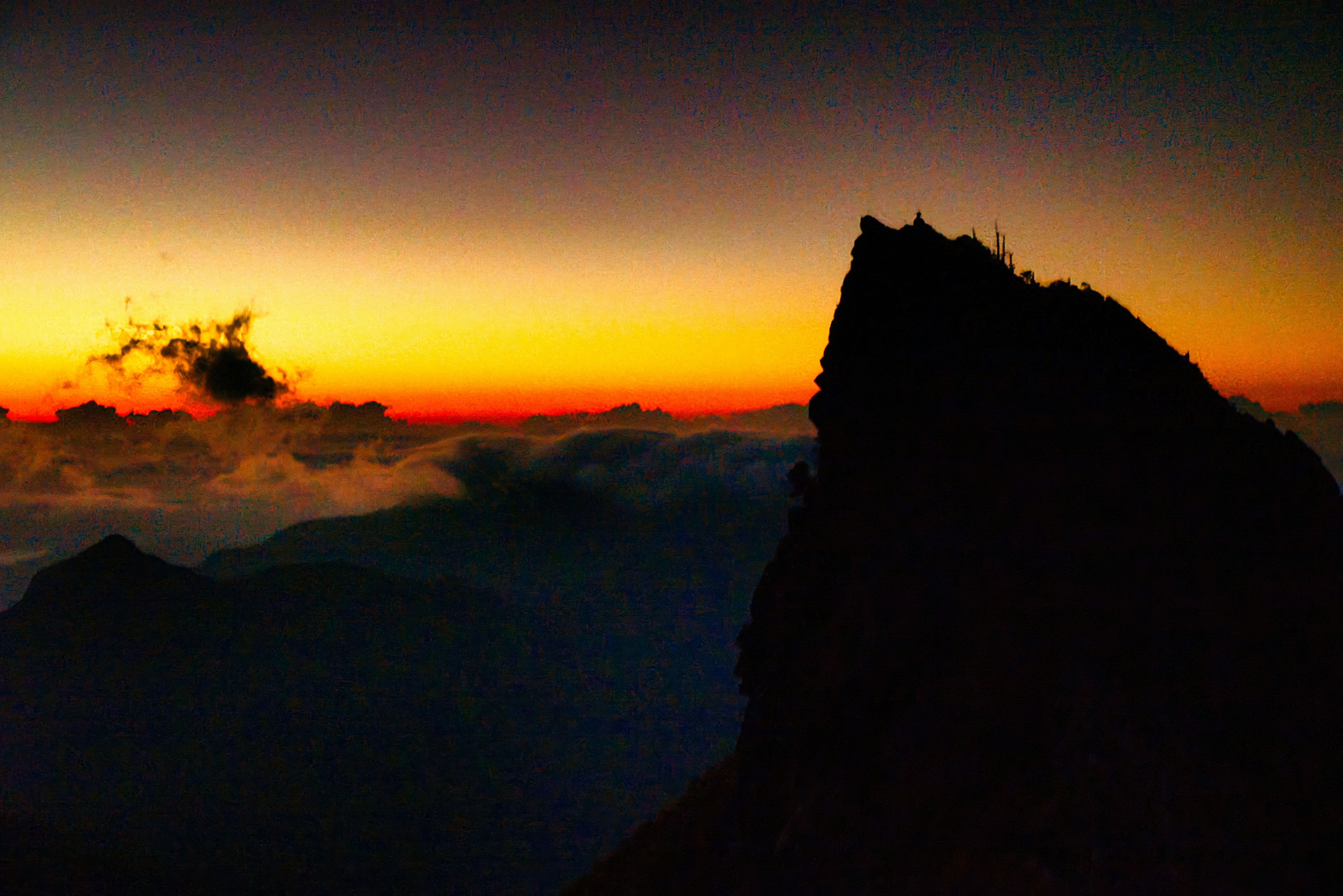 Silueta de una montaña al atardecer con nubes de fondo