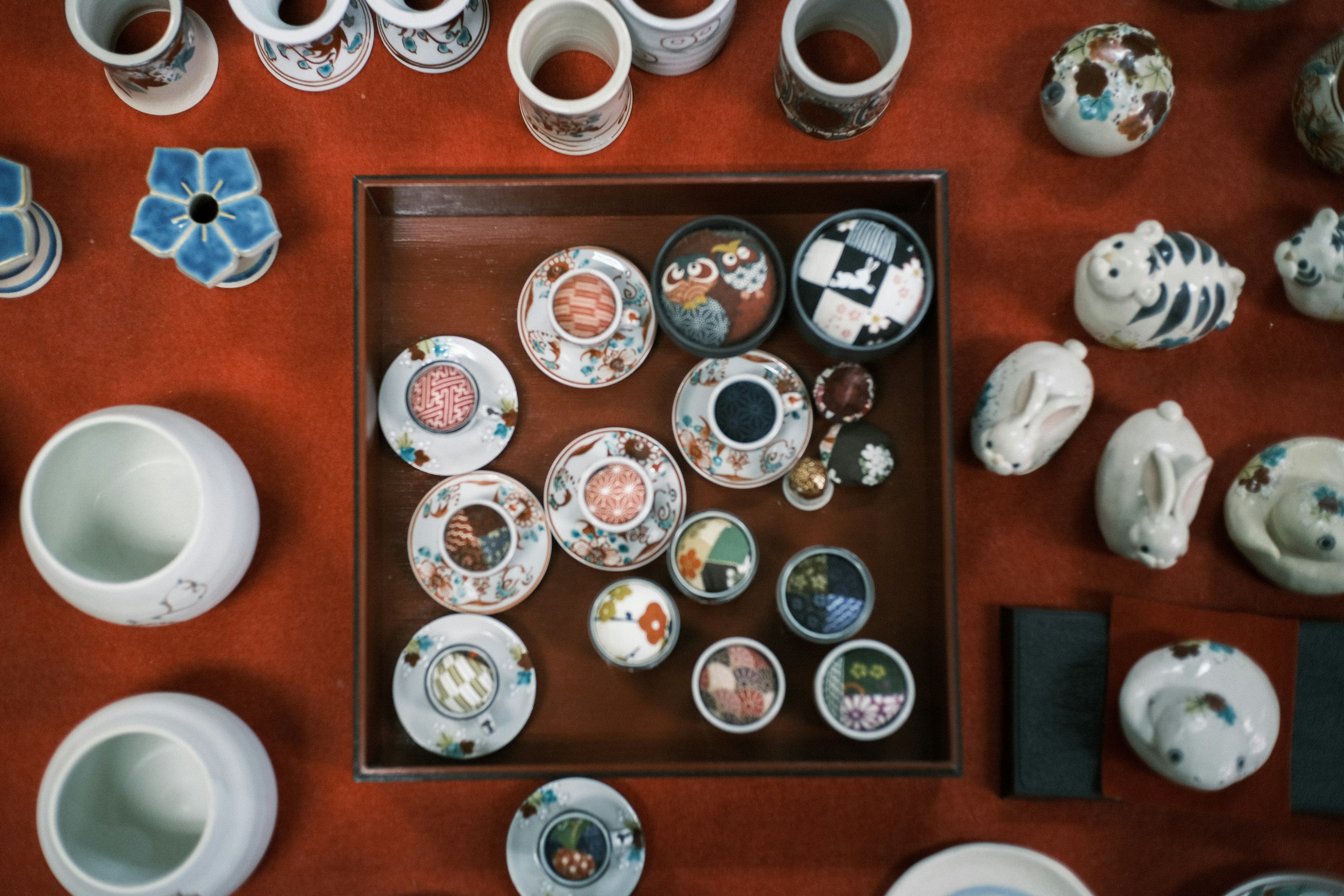 Collection de plaques en céramique et petits objets sur un tissu rouge