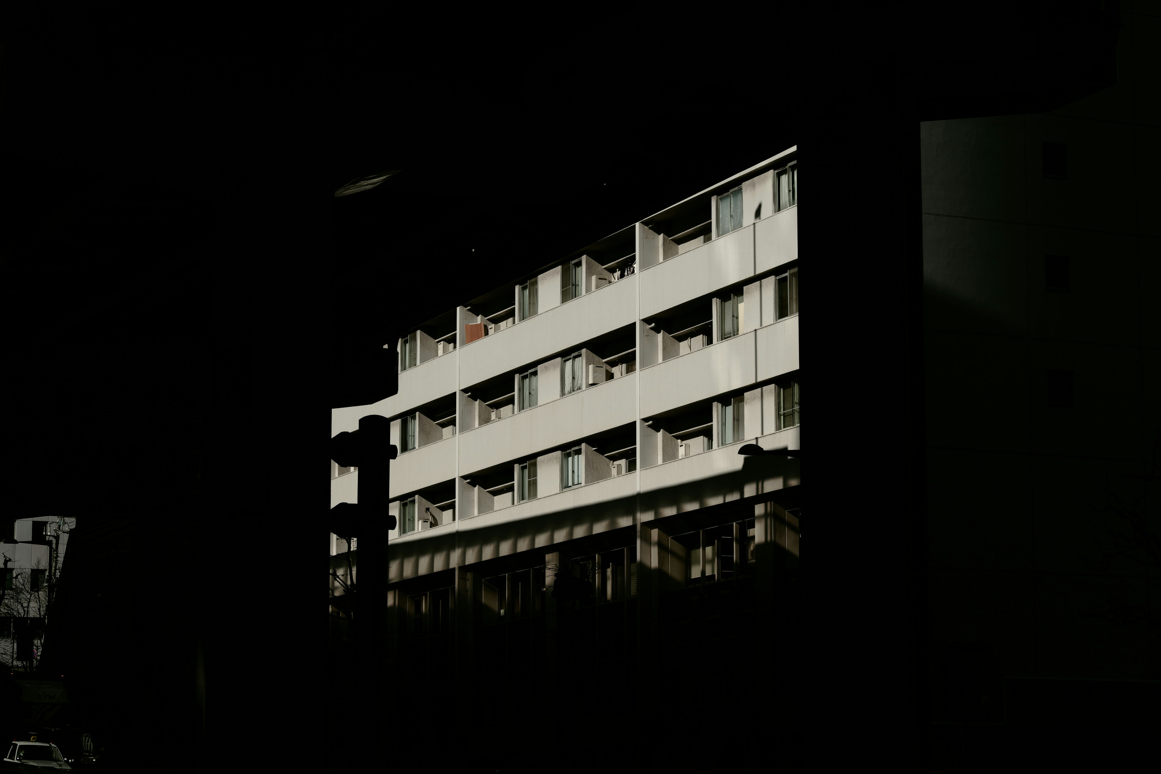 Exterior view of a white apartment building against a dark background