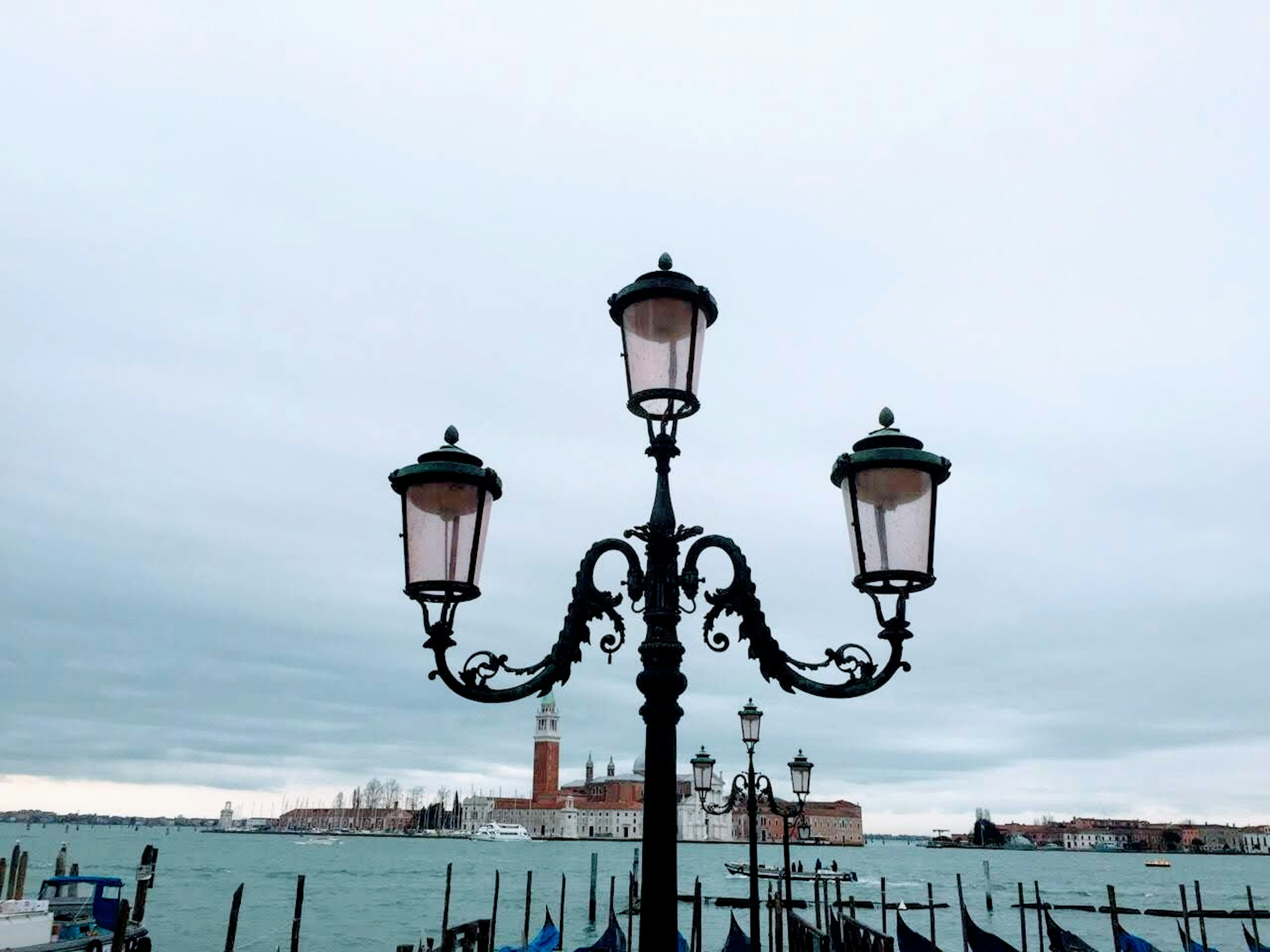 Đèn đường trang trí bên bờ nước với cảnh Venice ở phía sau