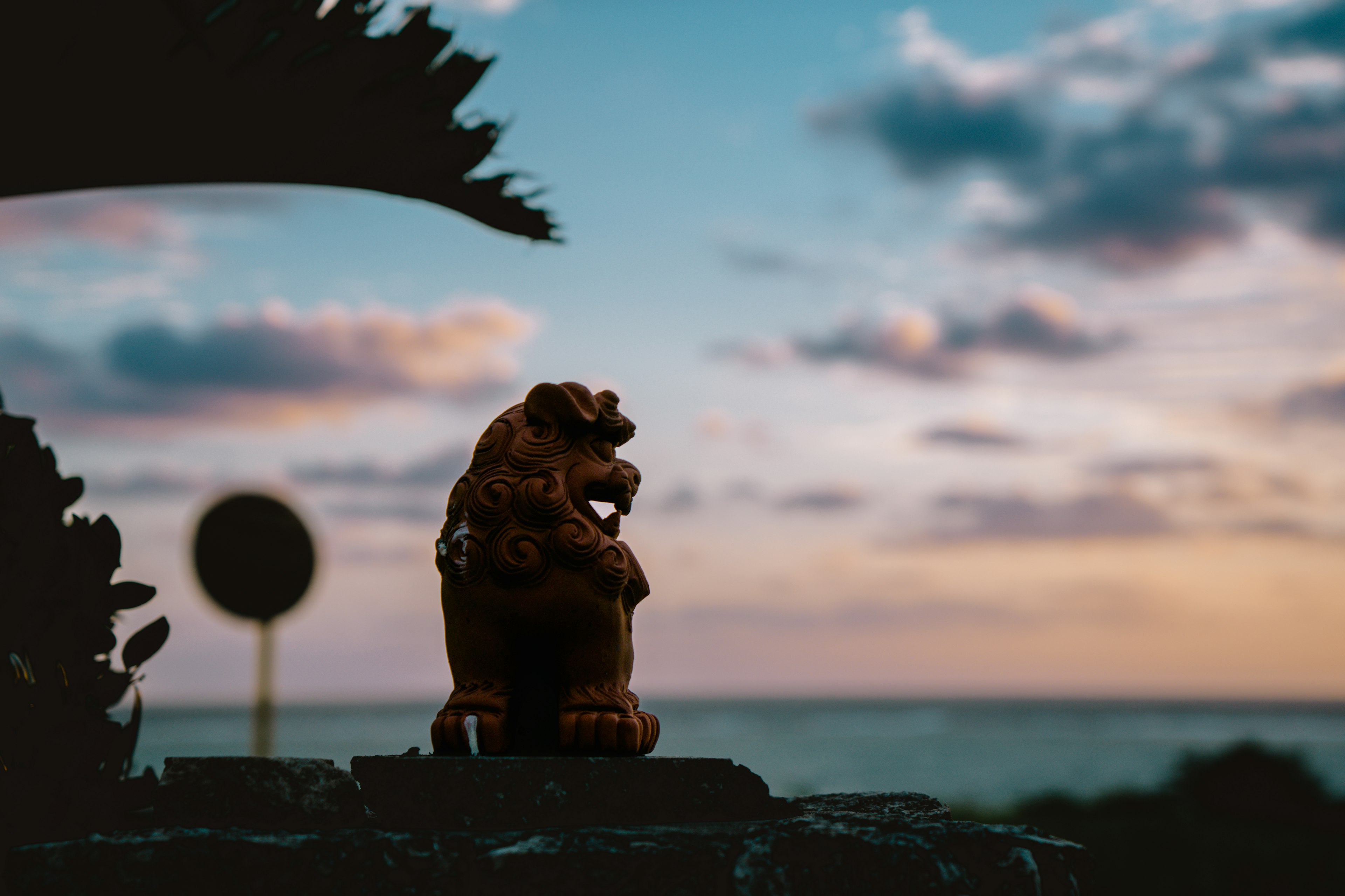 Estatua de león en silueta contra un atardecer sobre el océano