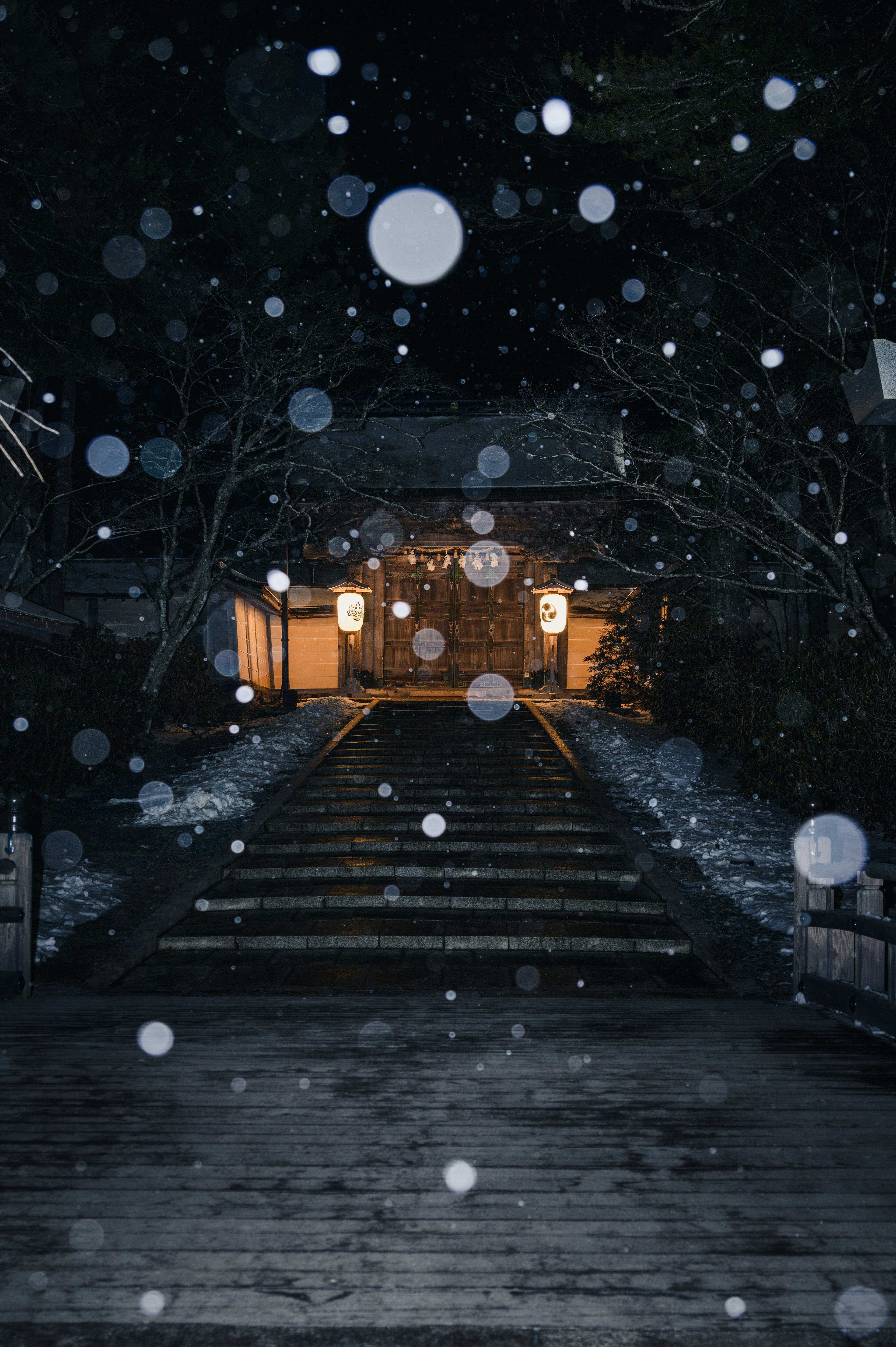 Puente que lleva a un santuario iluminado por la noche con nieve cayendo