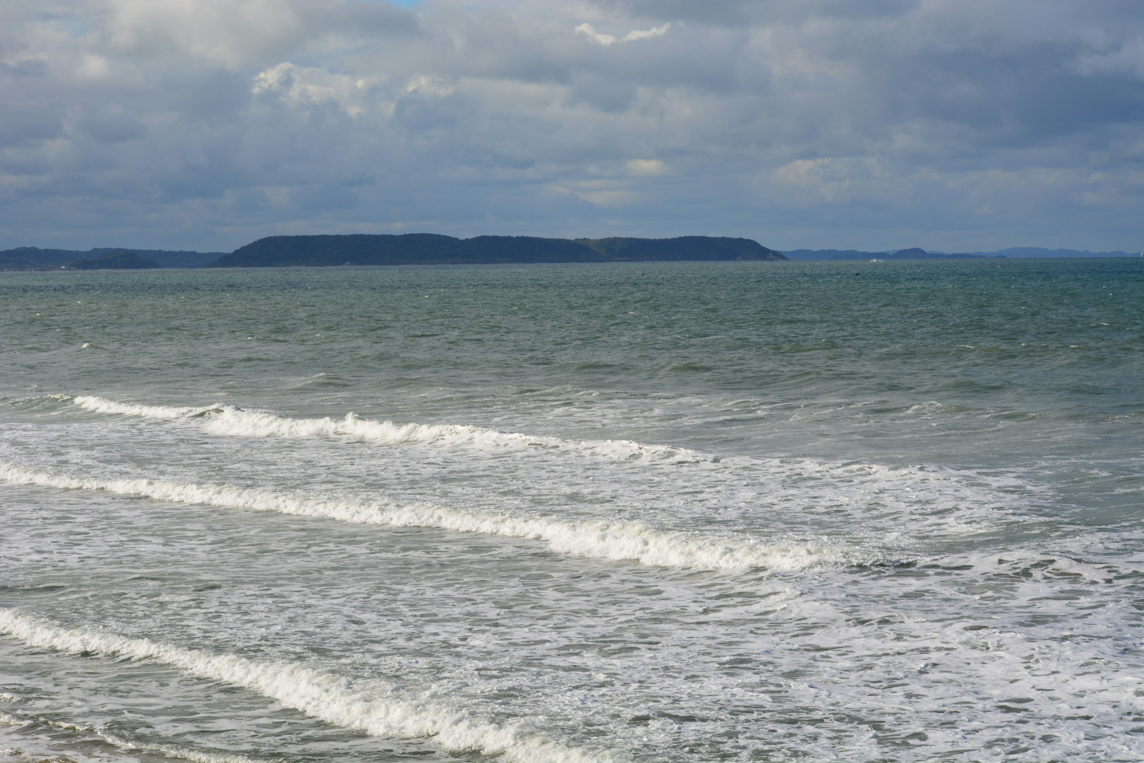 Vagues sur la mer sous un ciel nuageux avec une île au loin