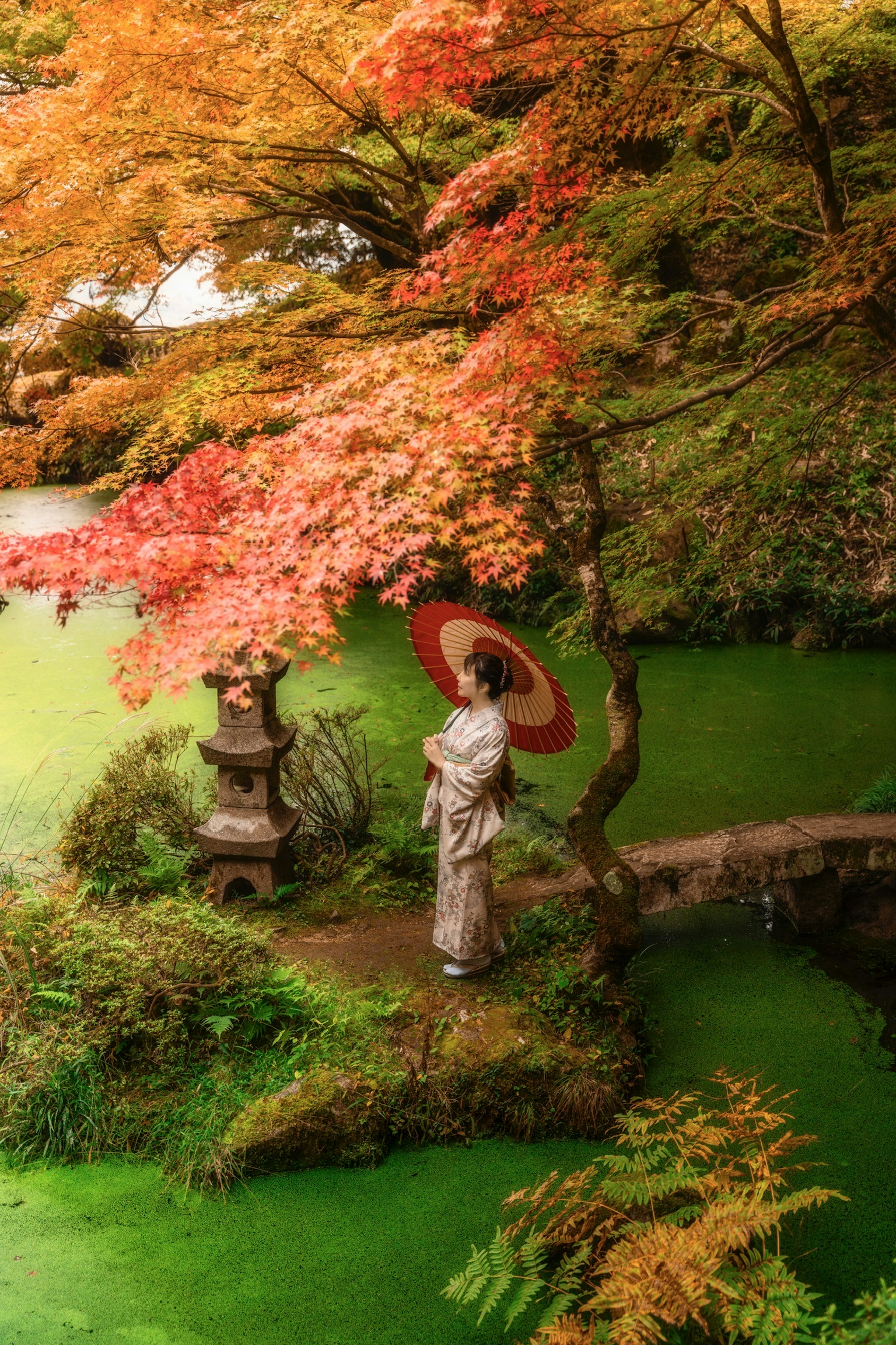 一位穿著傳統服裝的女性手持紅傘站在美麗的秋季花園中