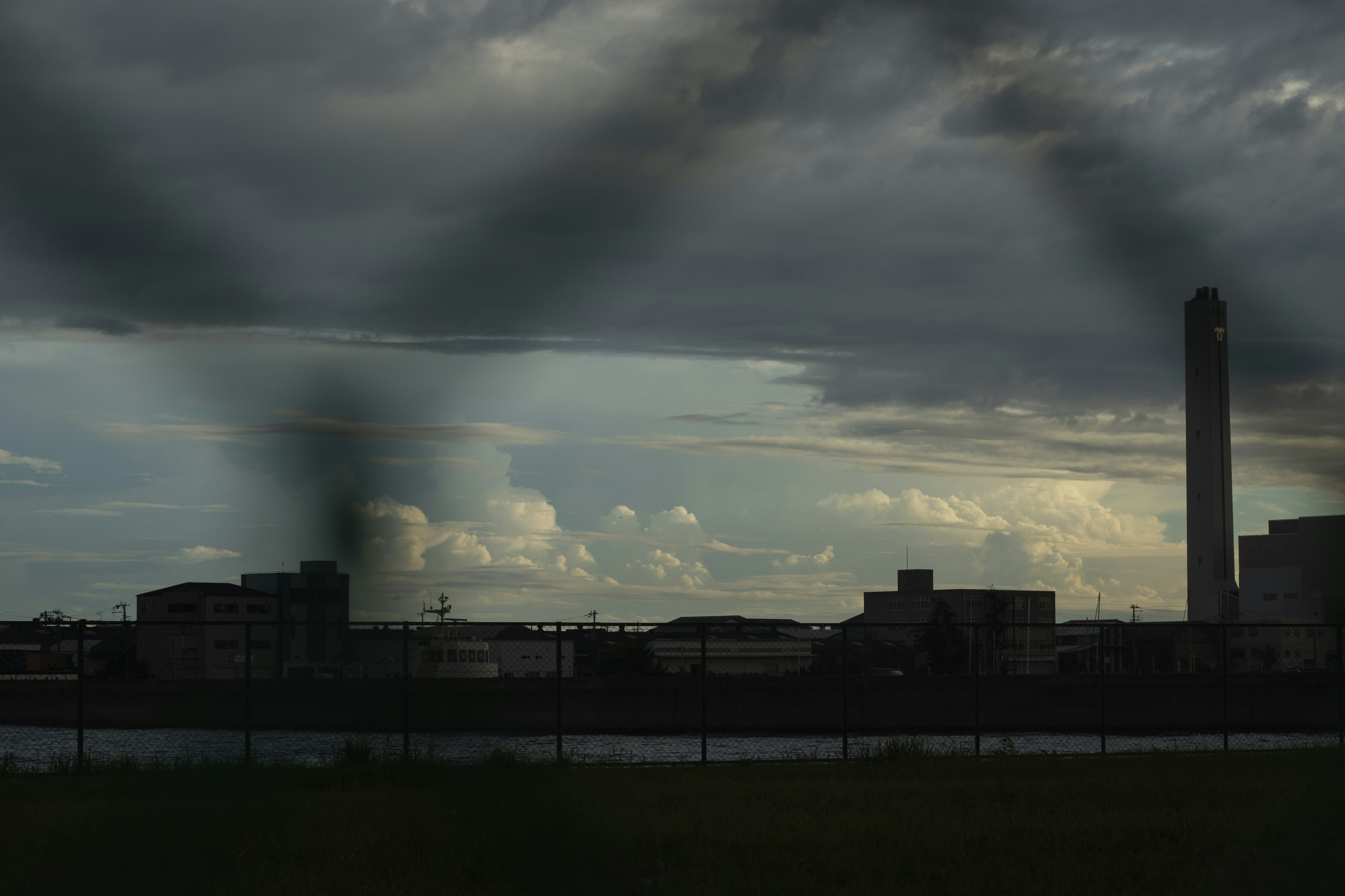 Silhouette d'une zone industrielle avec des nuages sombres