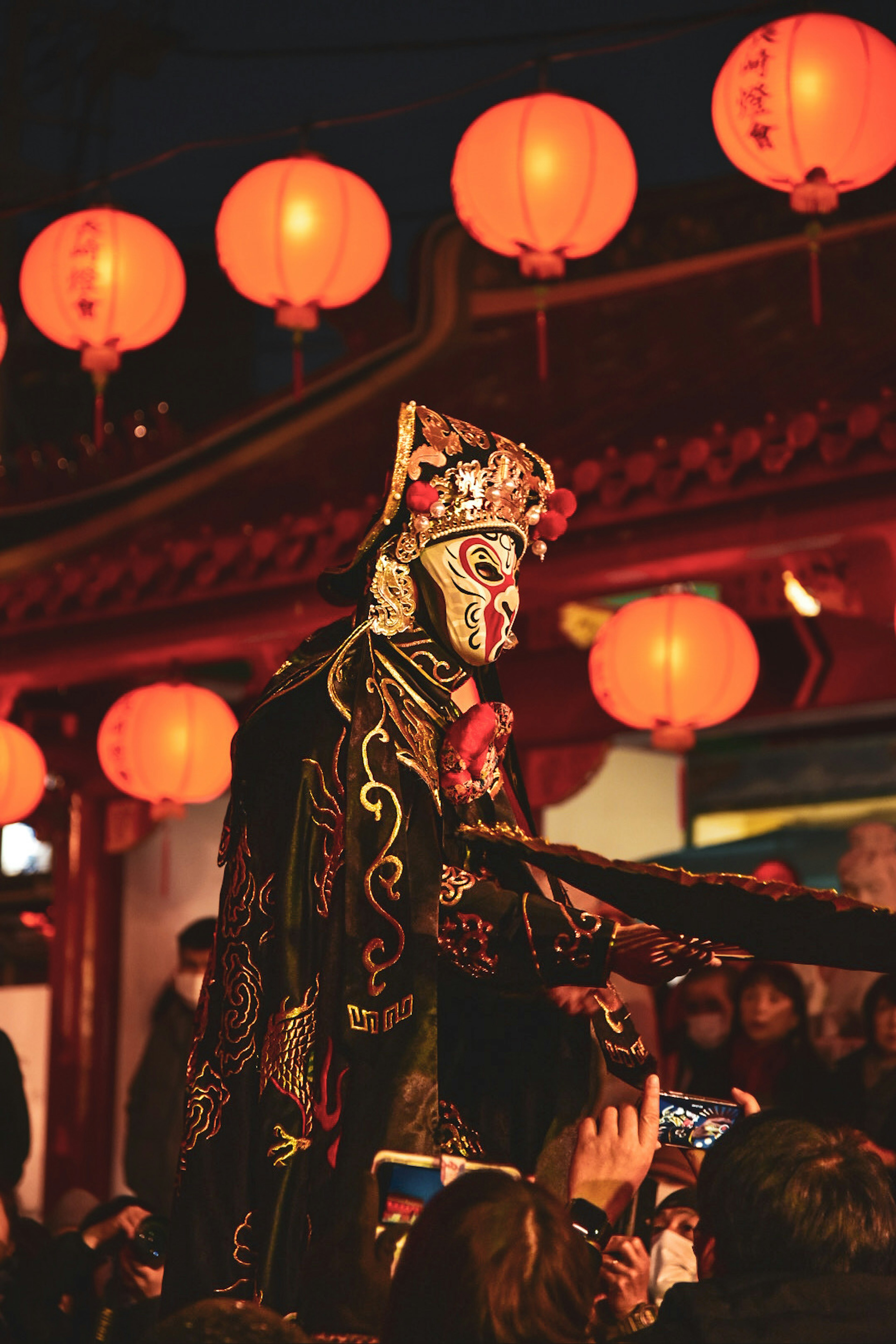 Artiste en costume traditionnel interagissant avec le public lors d'un festival nocturne