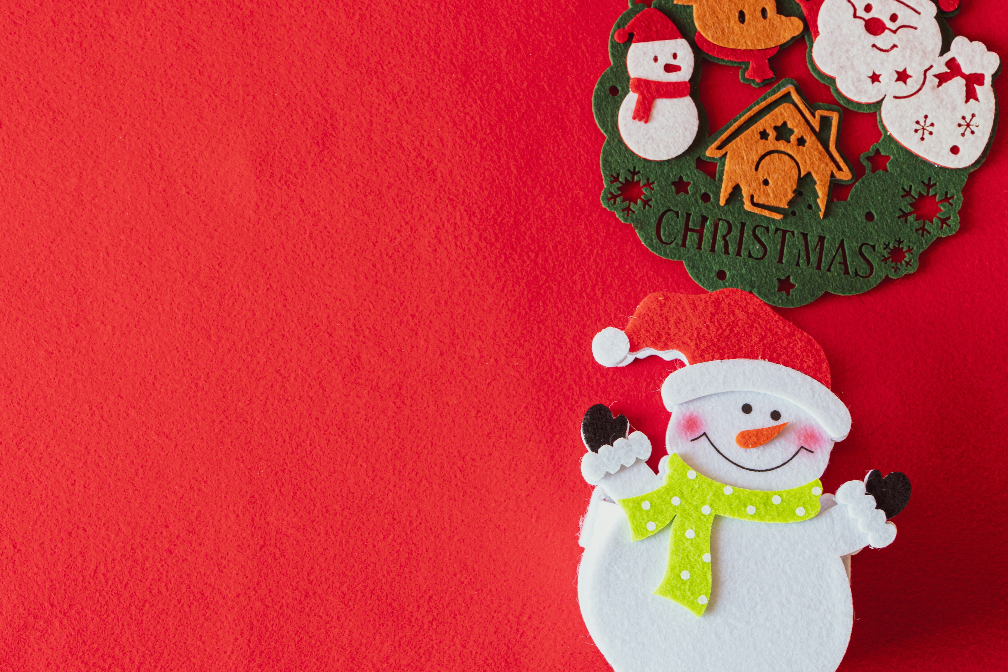 A snowman and Christmas wreath on a red background