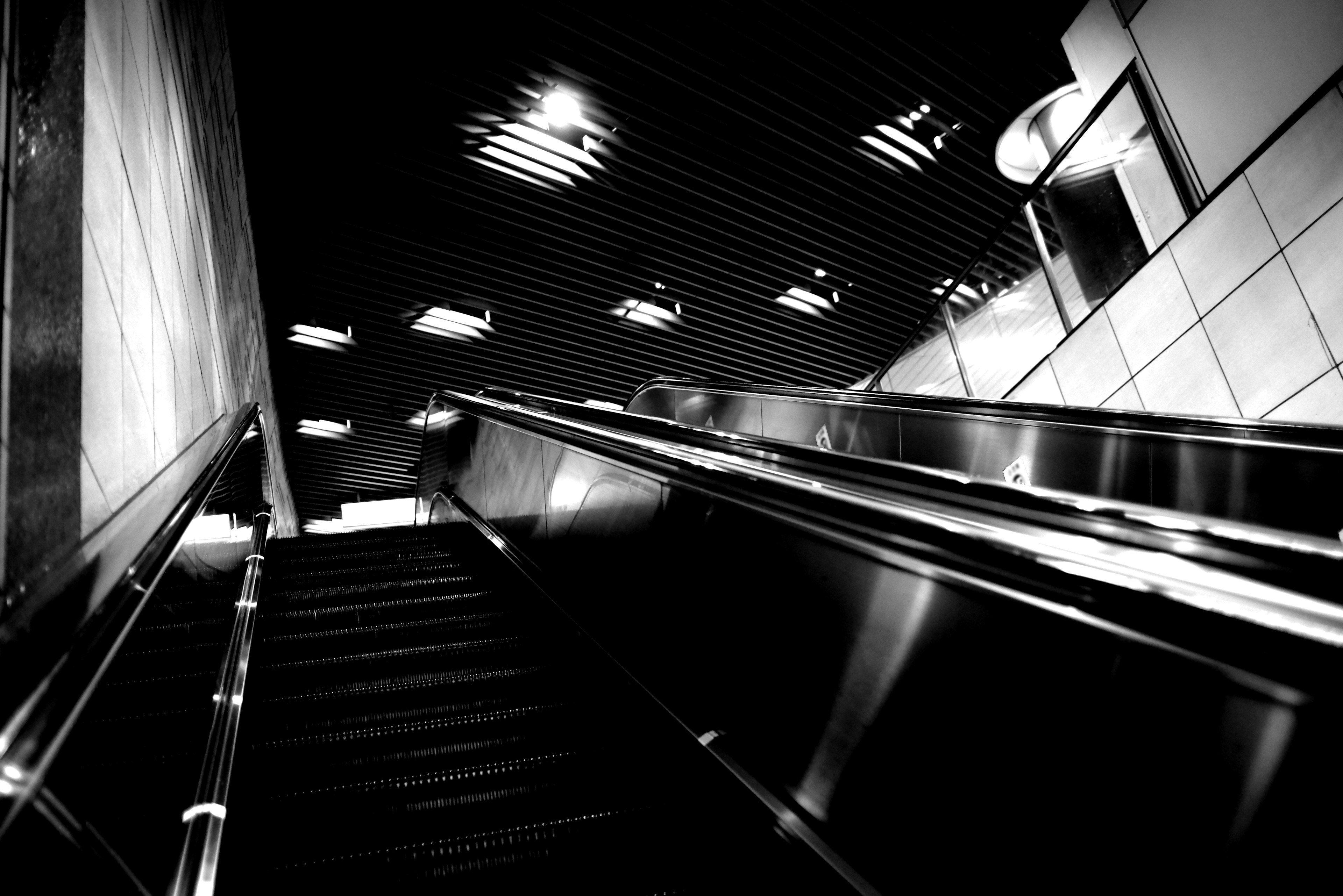 Monochrome view of an escalator with reflections and overhead lighting