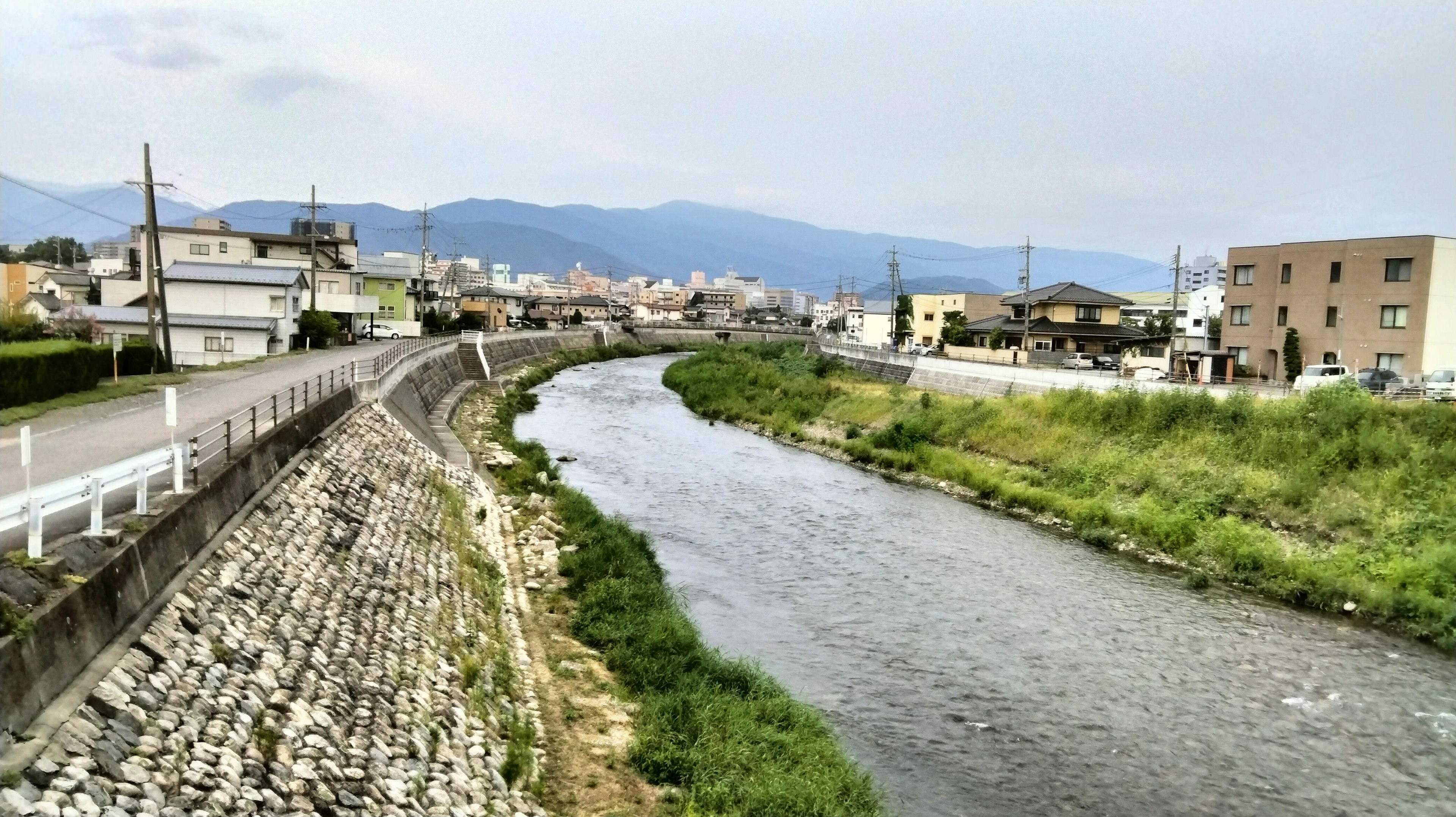 Vista escénica de un río con edificios y montañas al fondo