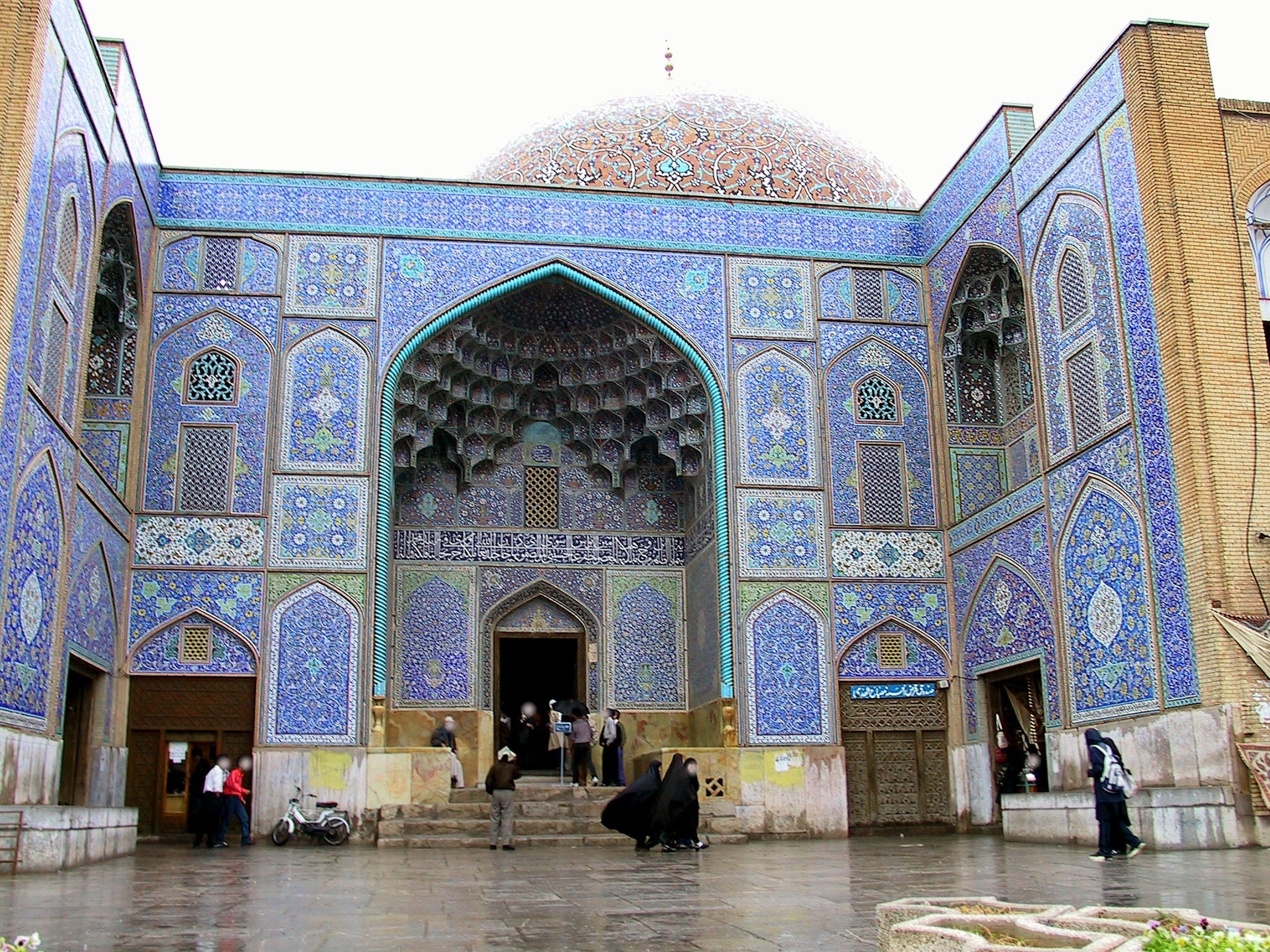 Entrance of a beautifully decorated building with blue and white tiles and people gathering