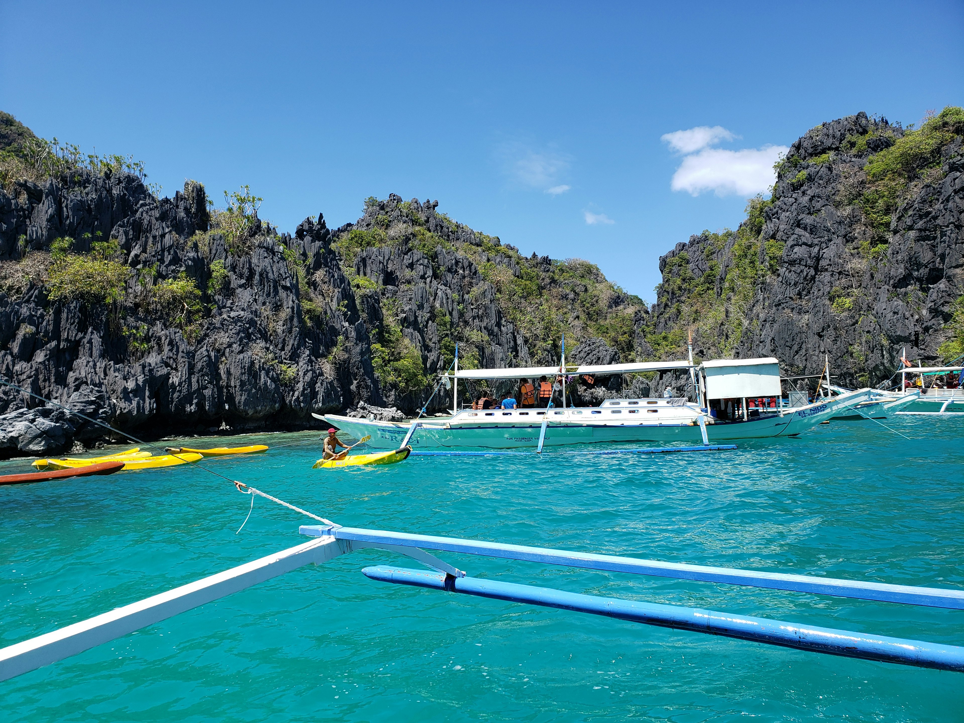 Scenic view of rocky cliffs with boats on a turquoise sea