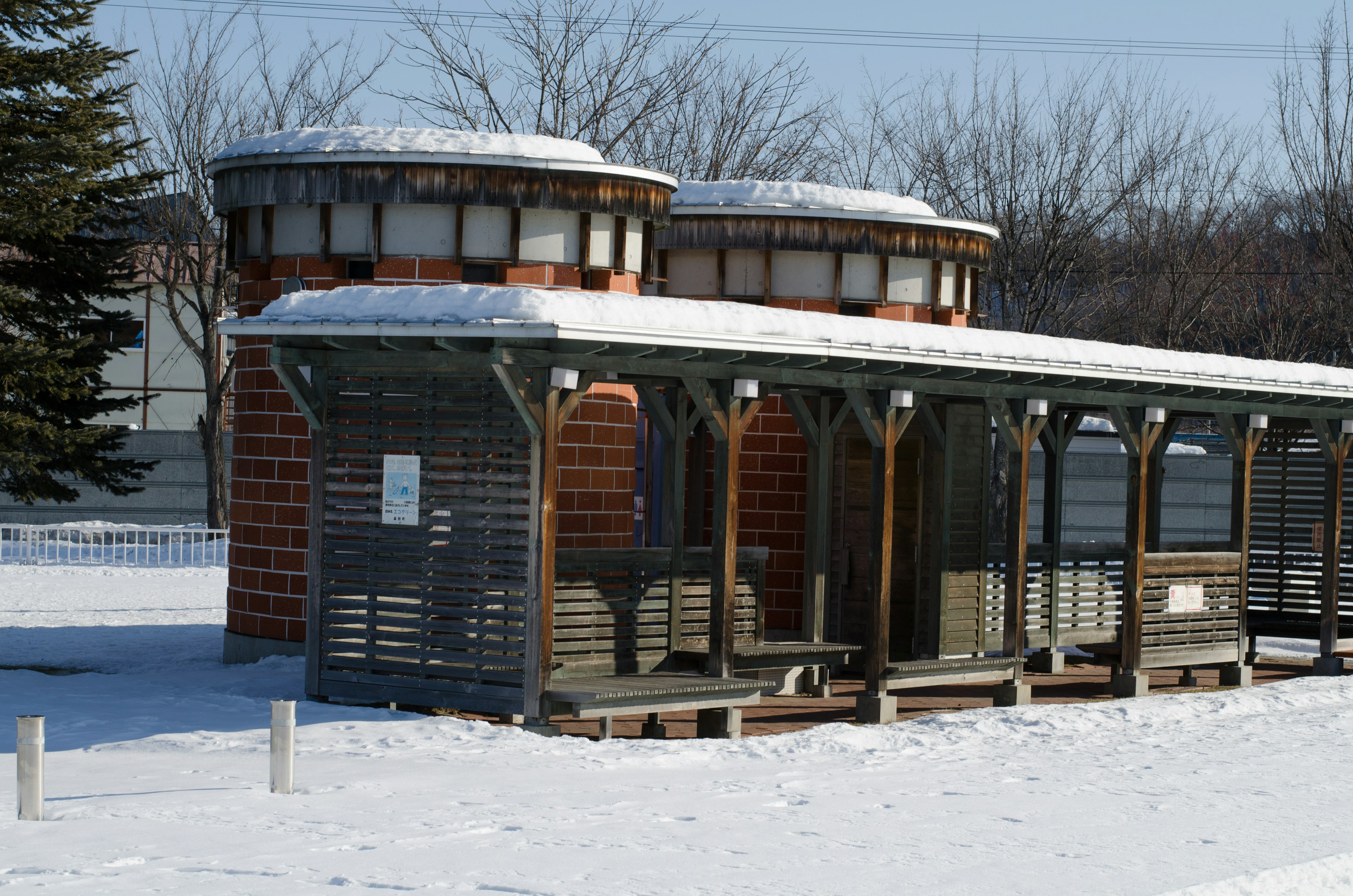 Snow-covered bus stop structure with wooden benches