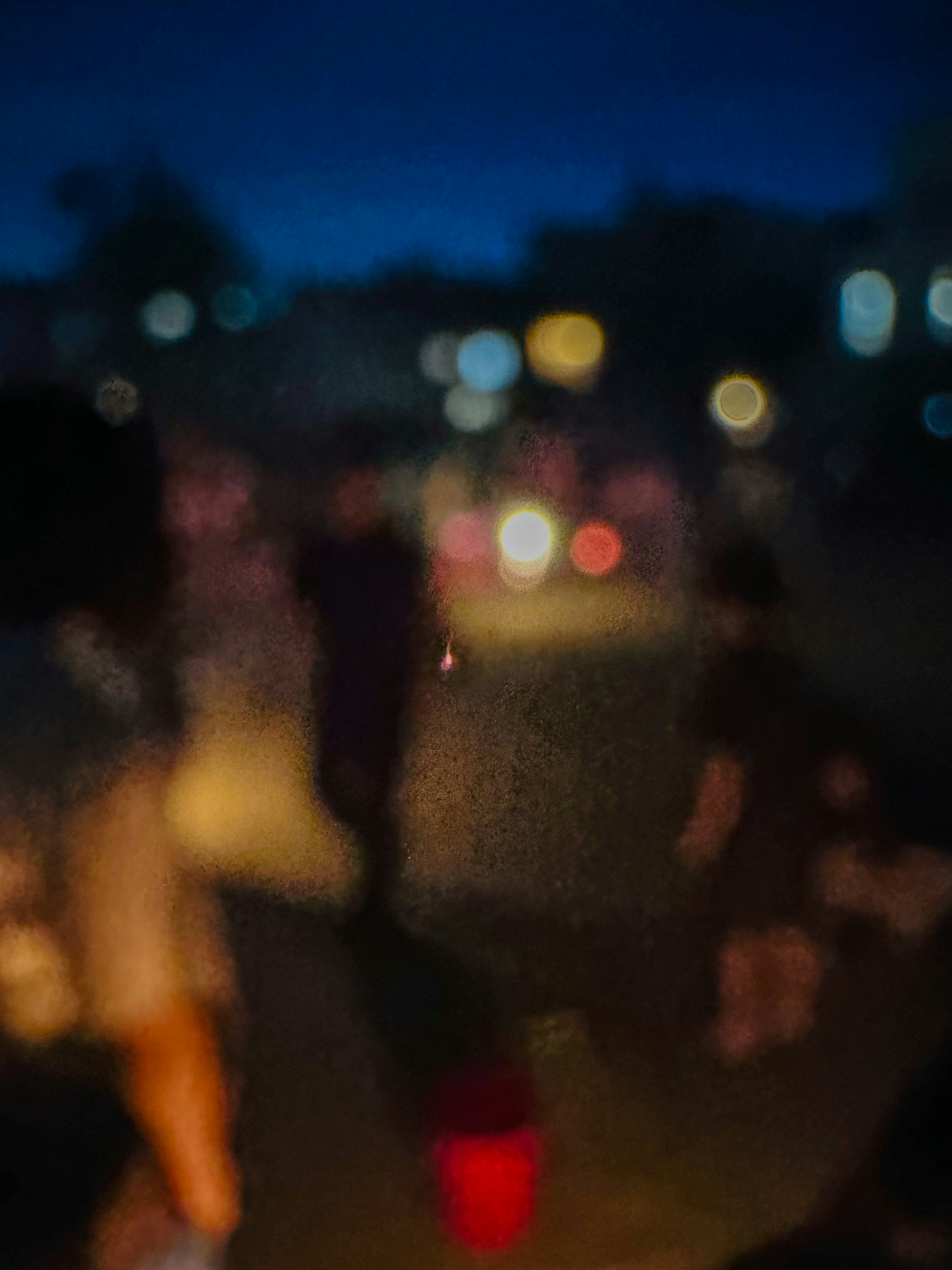 People gathering in a dimly lit street at night with blurred lights