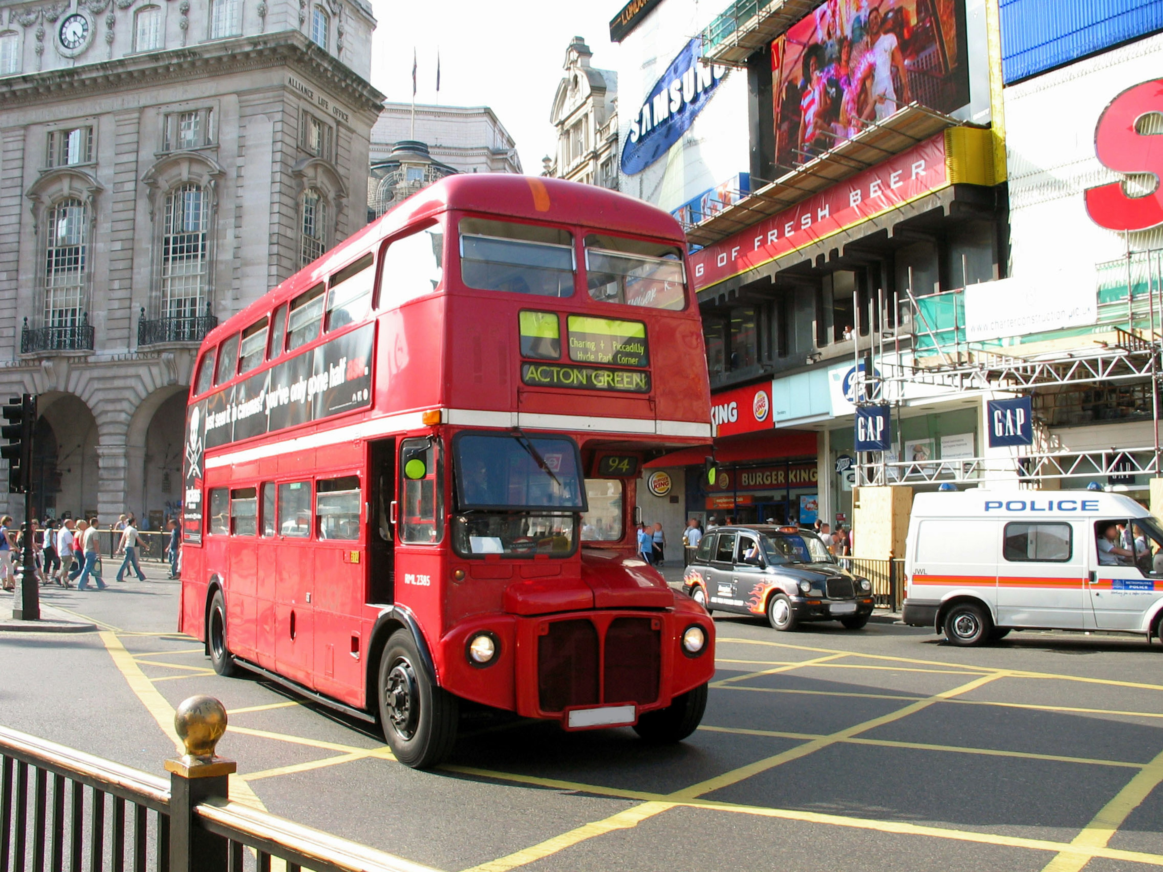 Ein roter Doppeldeckerbus fährt durch eine belebte Straße in London