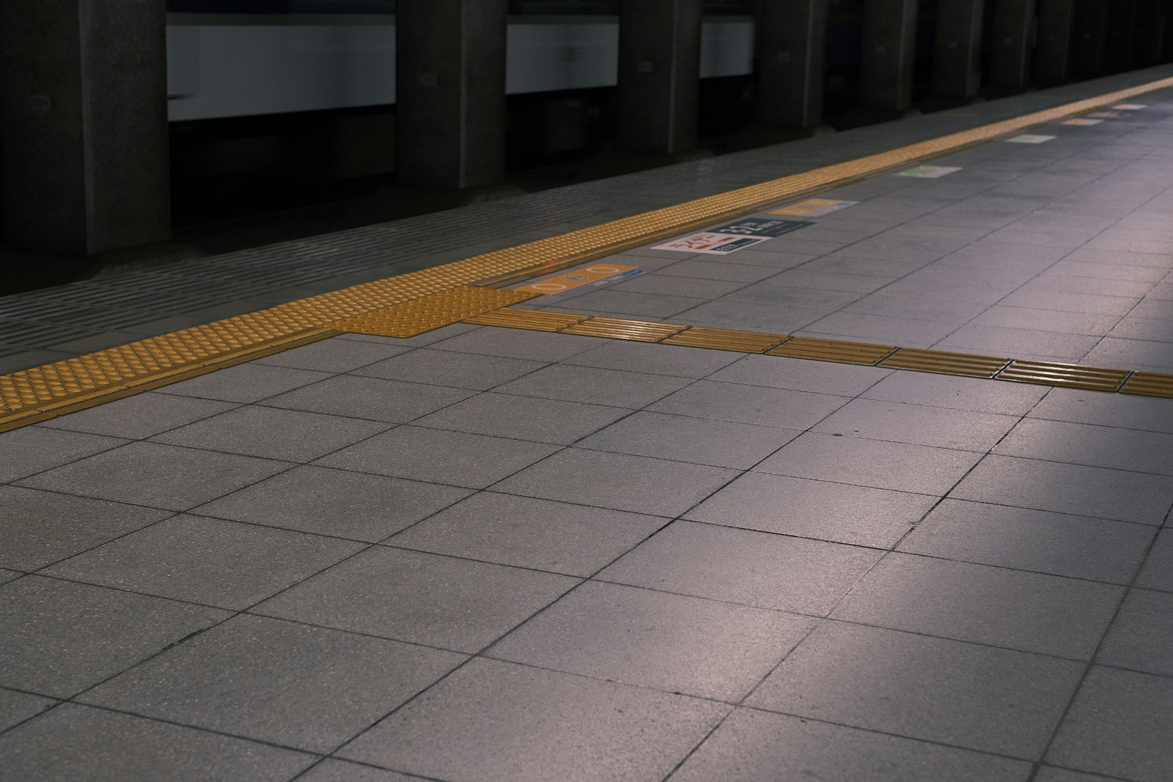 Train station platform with tiled floor and yellow safety line